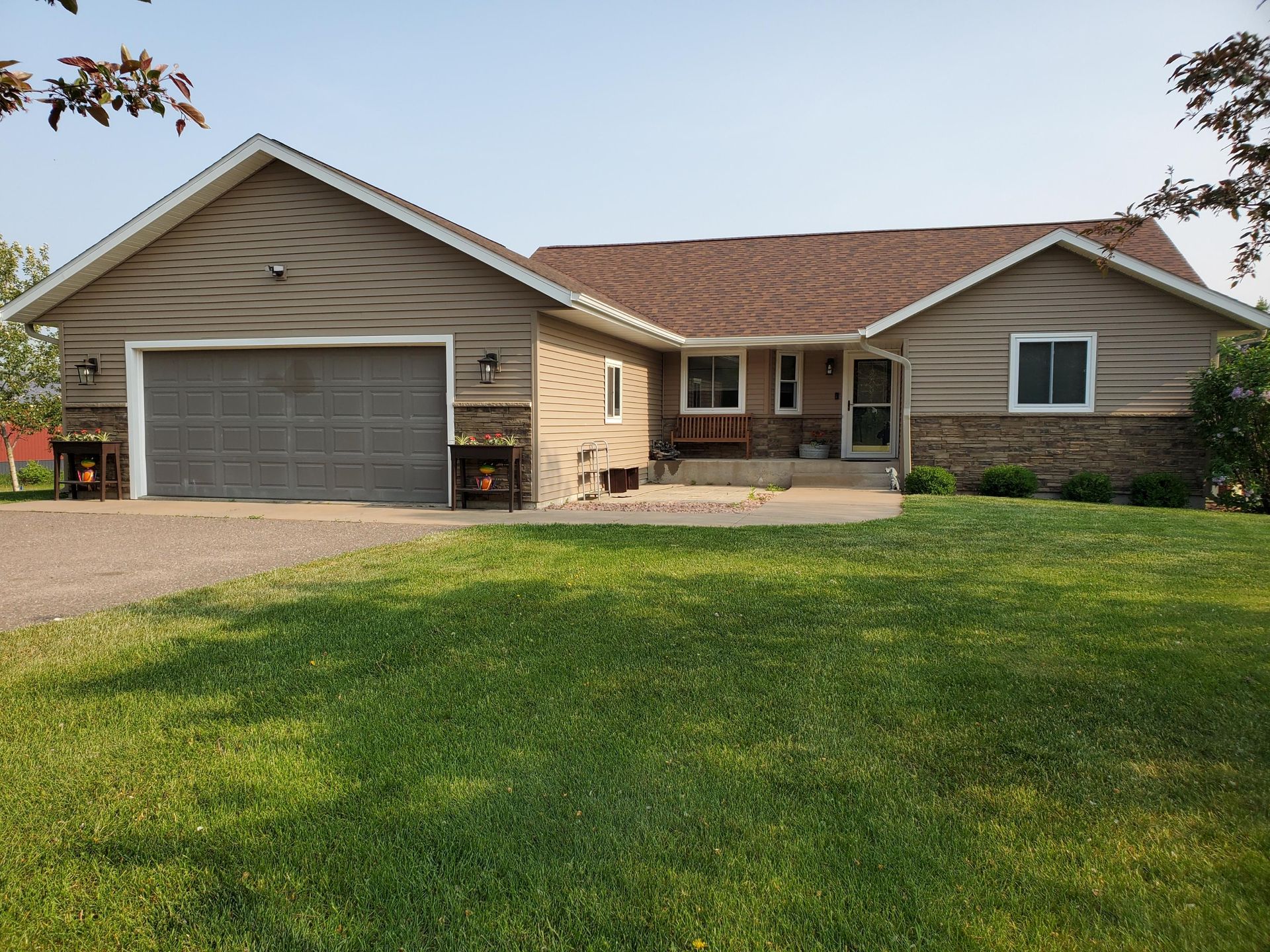 A house with a large garage and a large lawn in front of it.