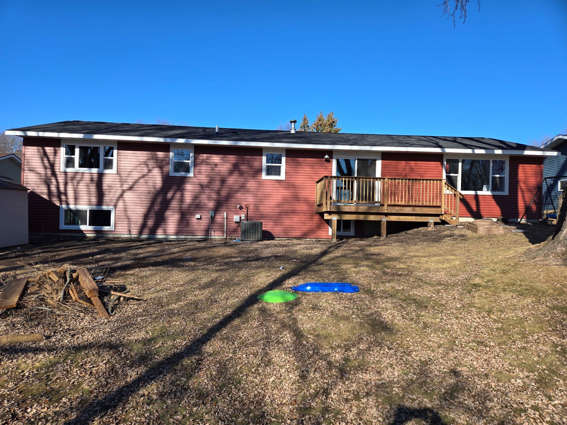 A red house with a deck and a frisbee in the backyard.