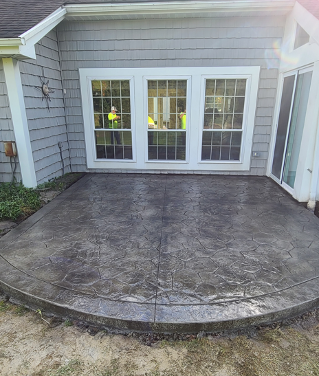 Stamped concrete patio in front of white French doors and windows on a house exterior