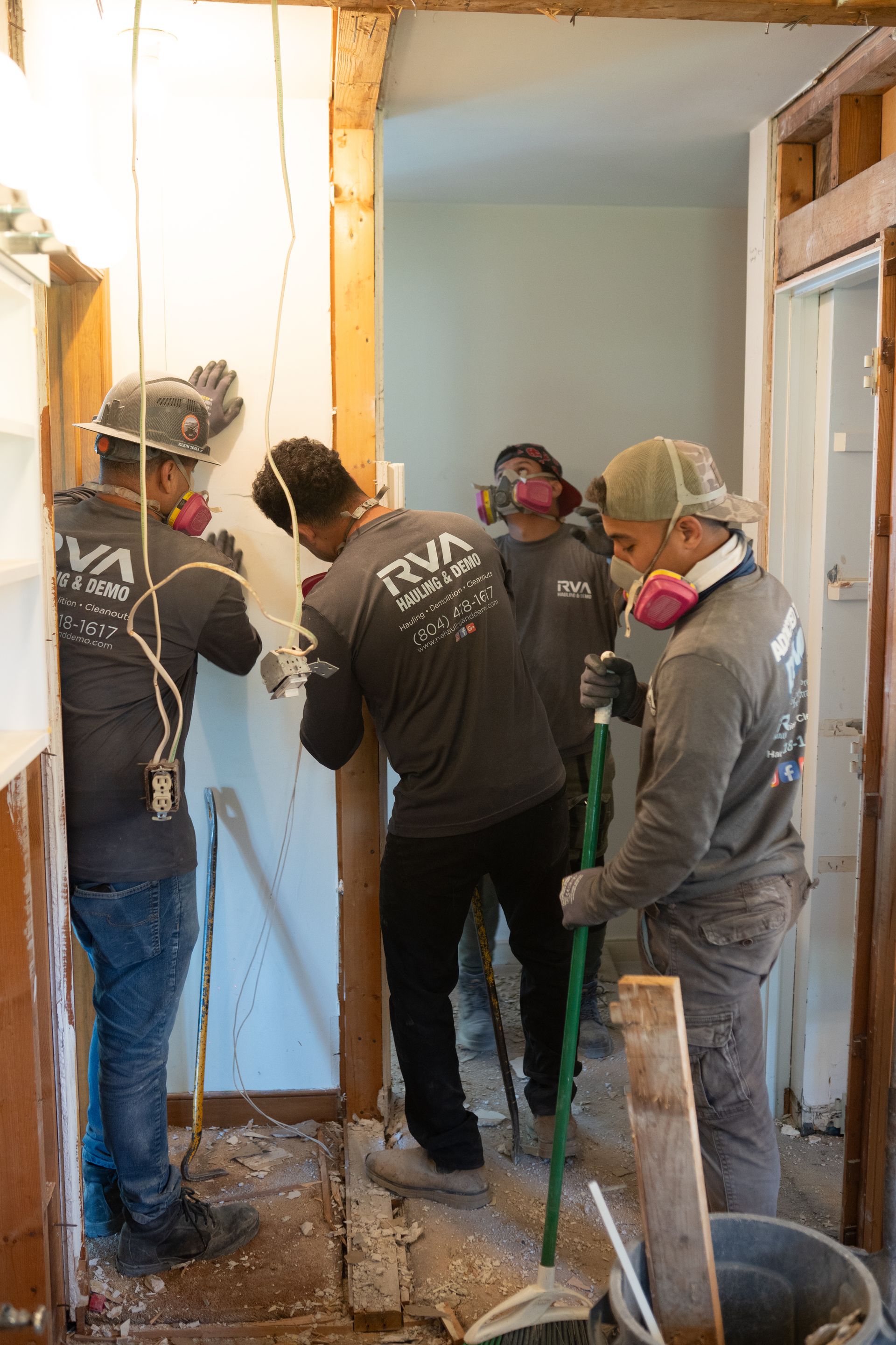 Workers using tools to remove a damaged interior wall in a doorway under renovation