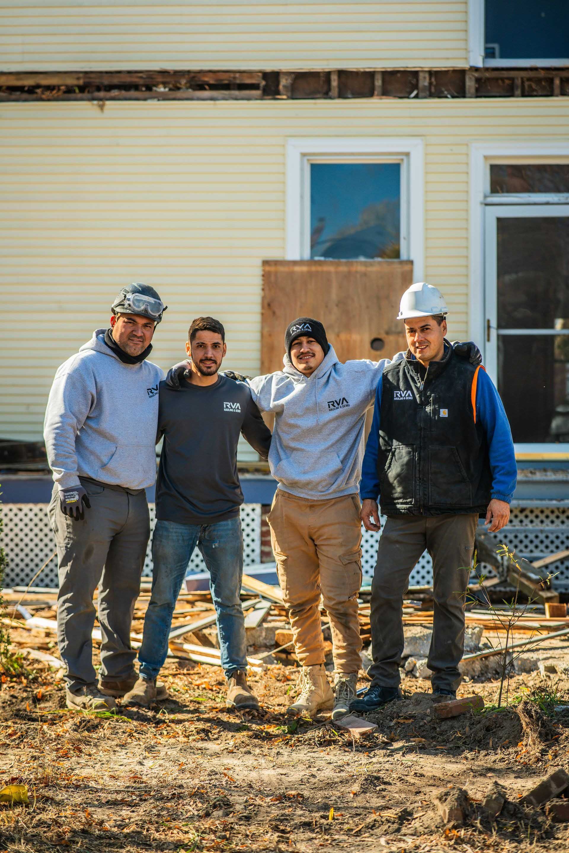 Four workers in hard hats standing outside a house under construction