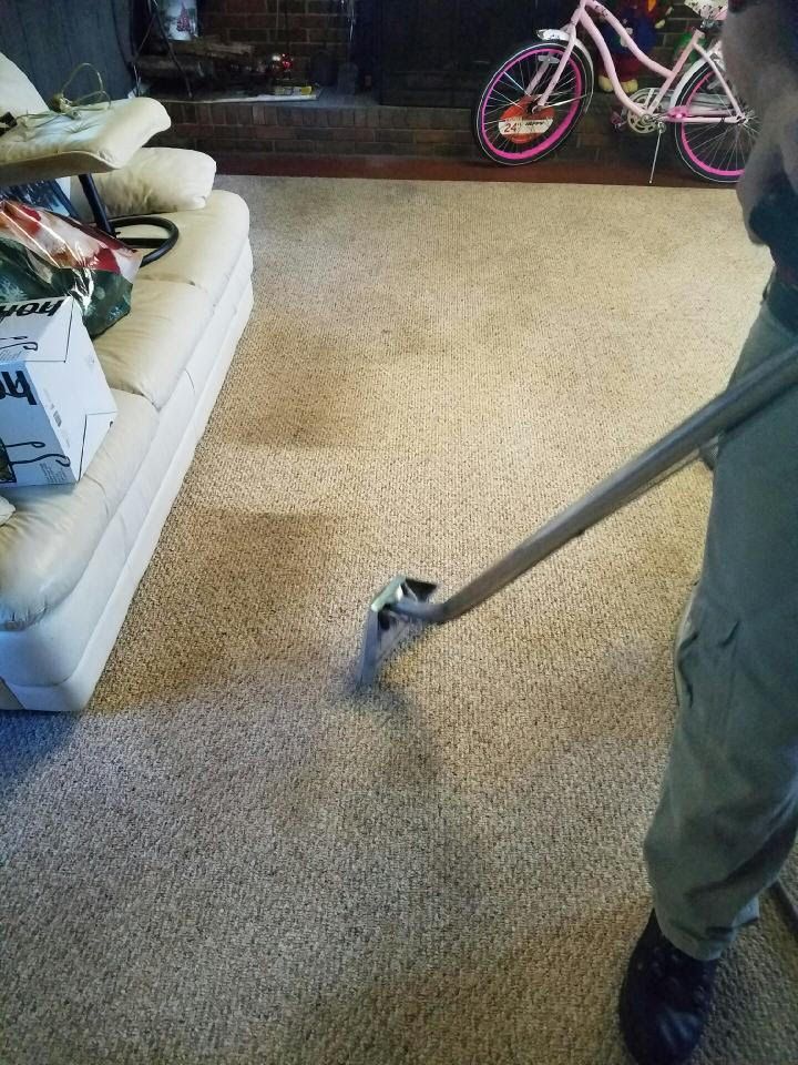A person is using a vacuum cleaner to clean a carpet in a living room.