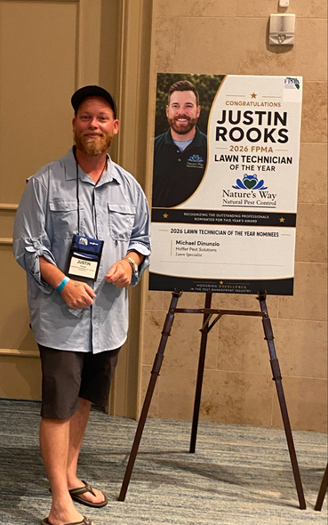 Man standing beside a Justin Rooks poster on an easel in a conference hallway