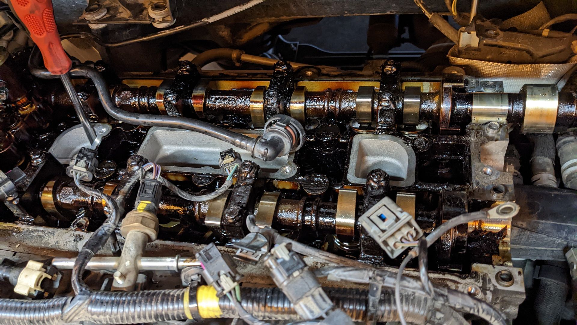 A close up of a car engine with a lot of oil on it.
