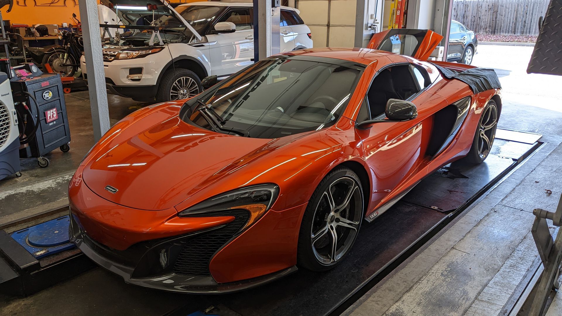 A red sports car is parked on a lift in a garage.