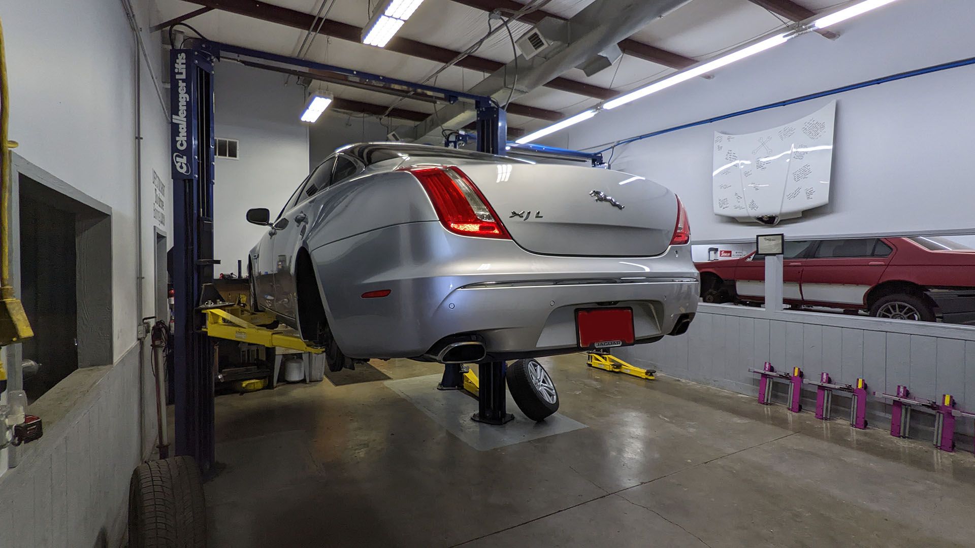 A silver car is sitting on a lift in a garage.