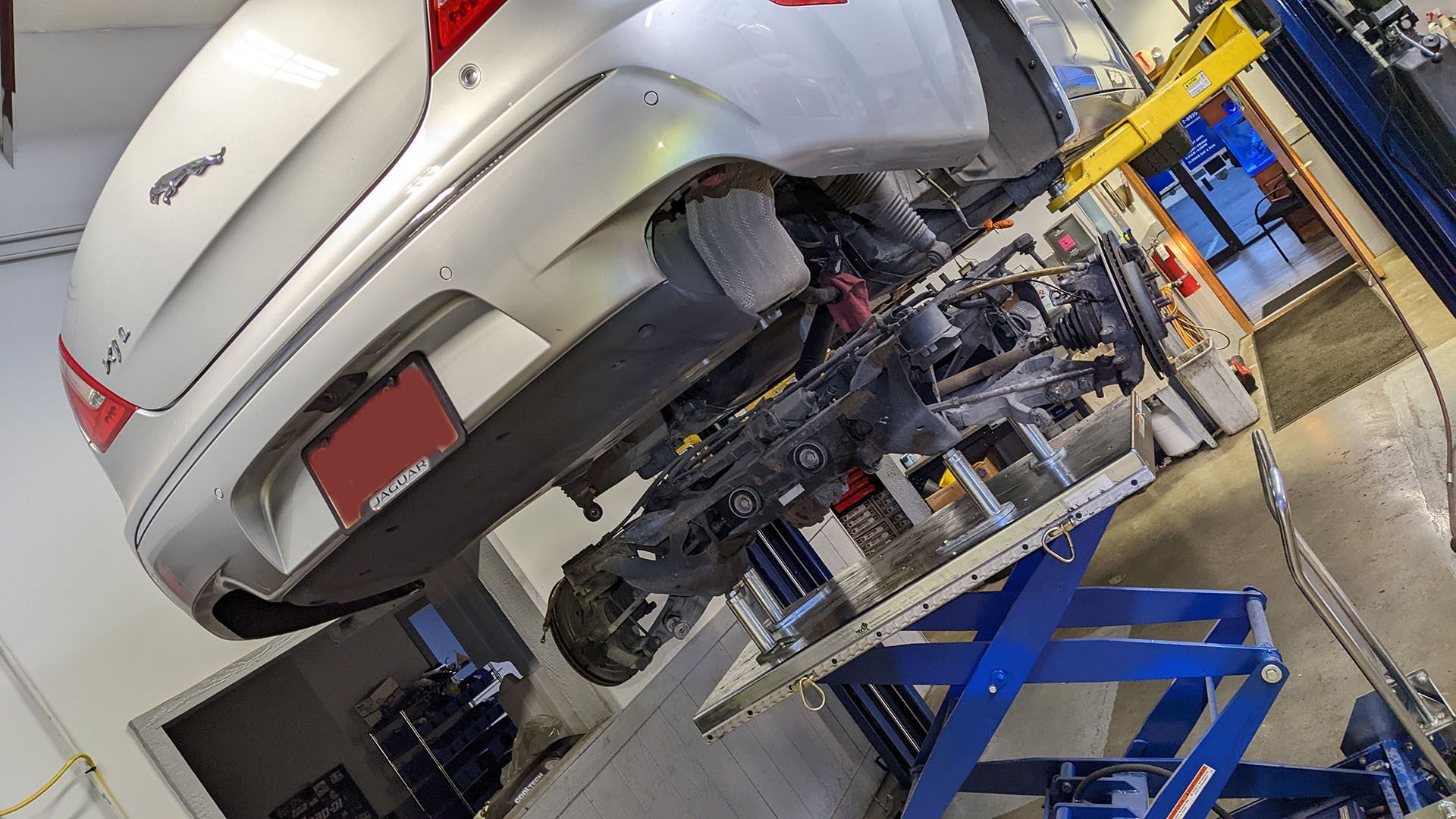 A car is sitting on a lift in a garage.