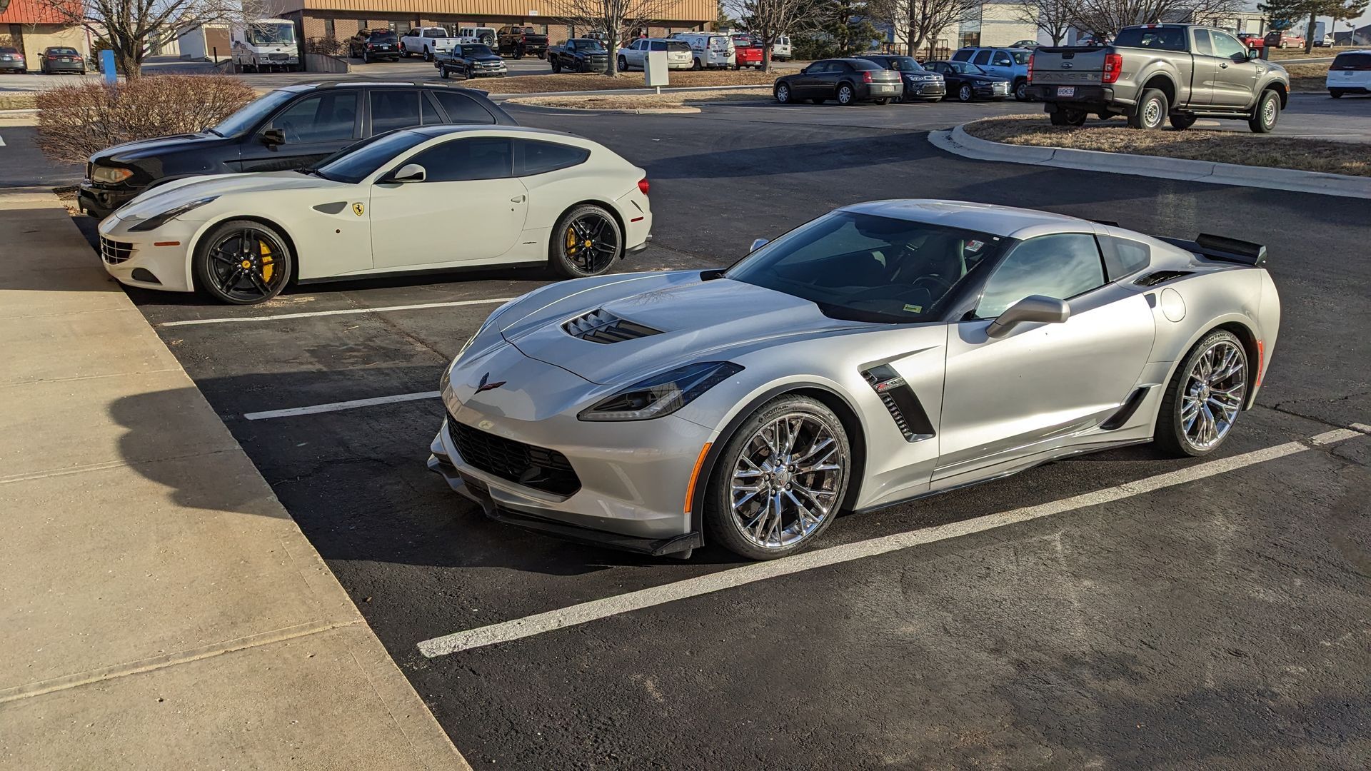 Three sports cars are parked in a parking lot.