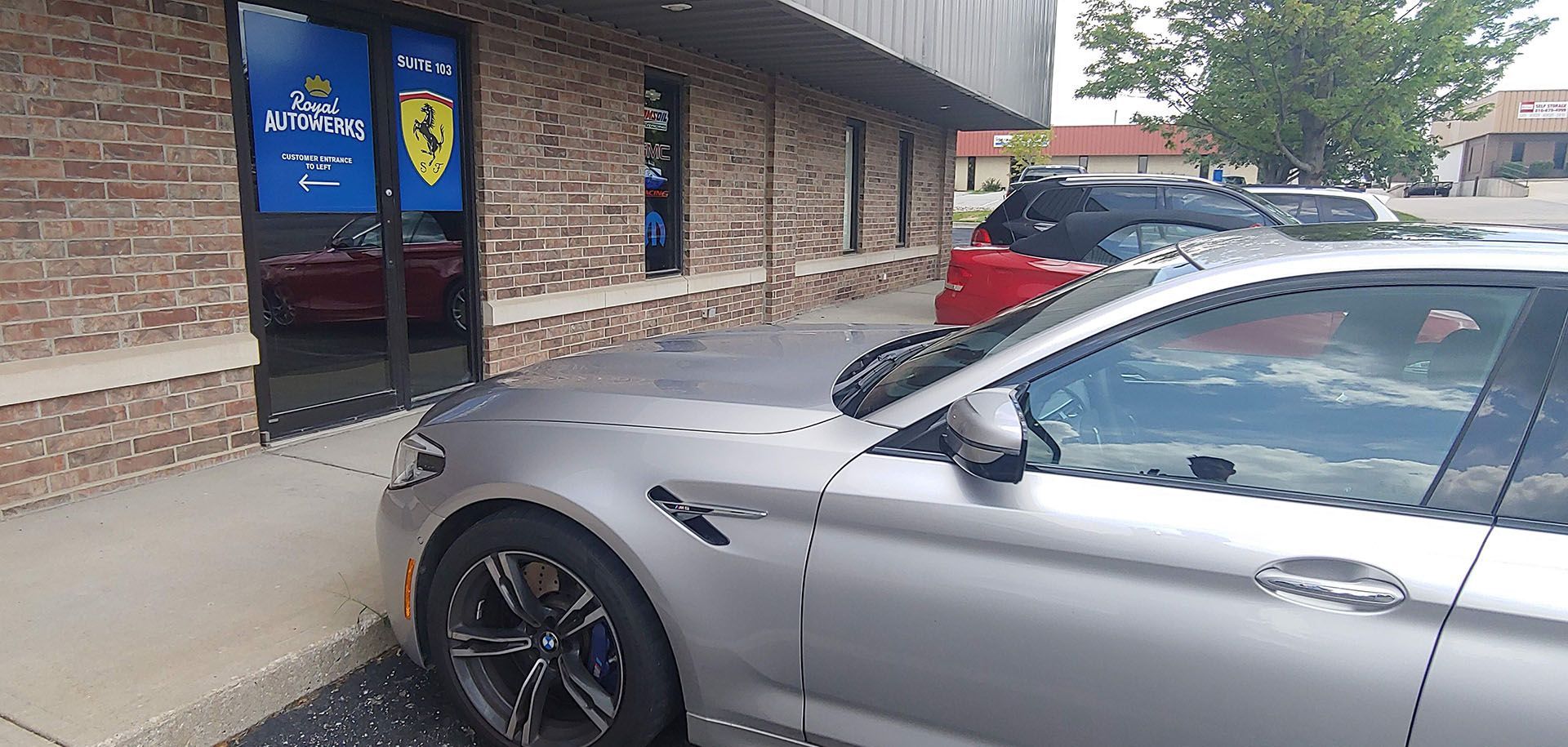 A silver car is parked in front of a brick building.