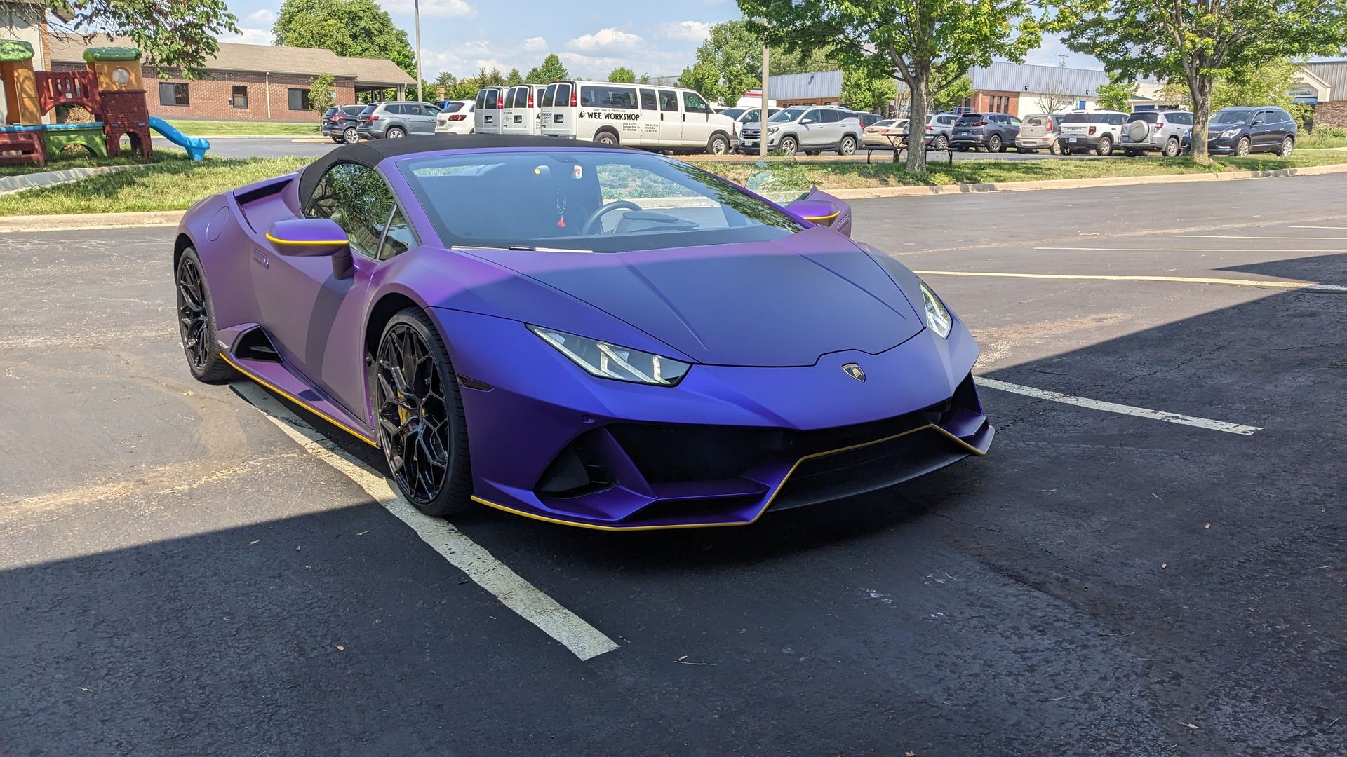 A purple lamborghini huracan is parked in a parking lot.