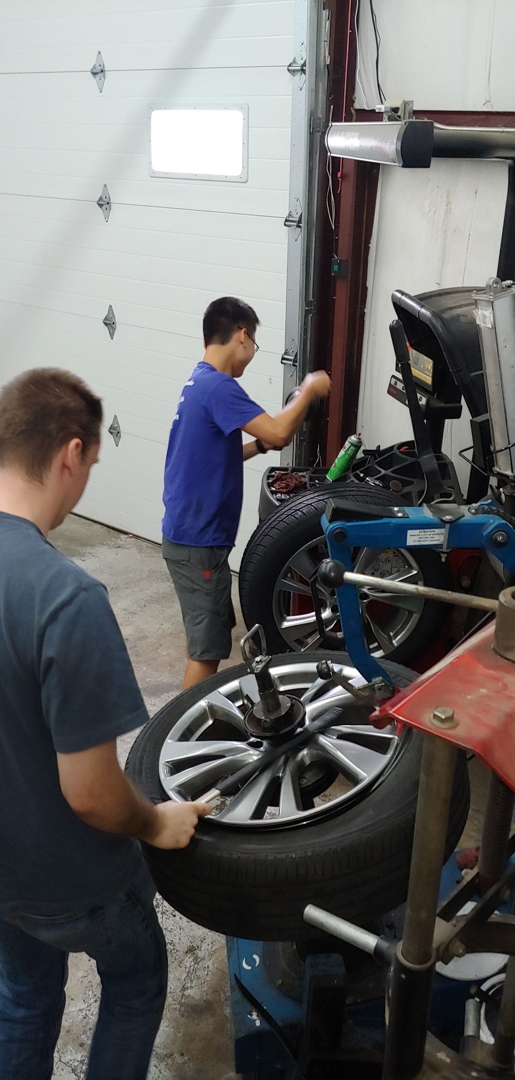 Two men are working on a tire in a garage.
