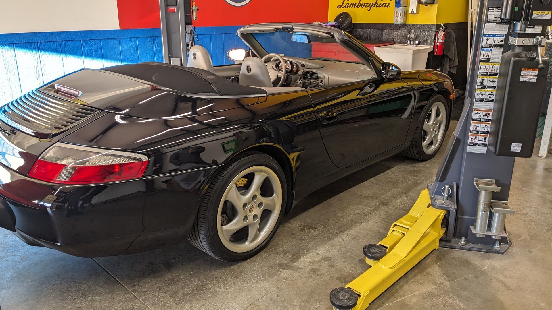 A black sports car is parked on a lift in a garage.