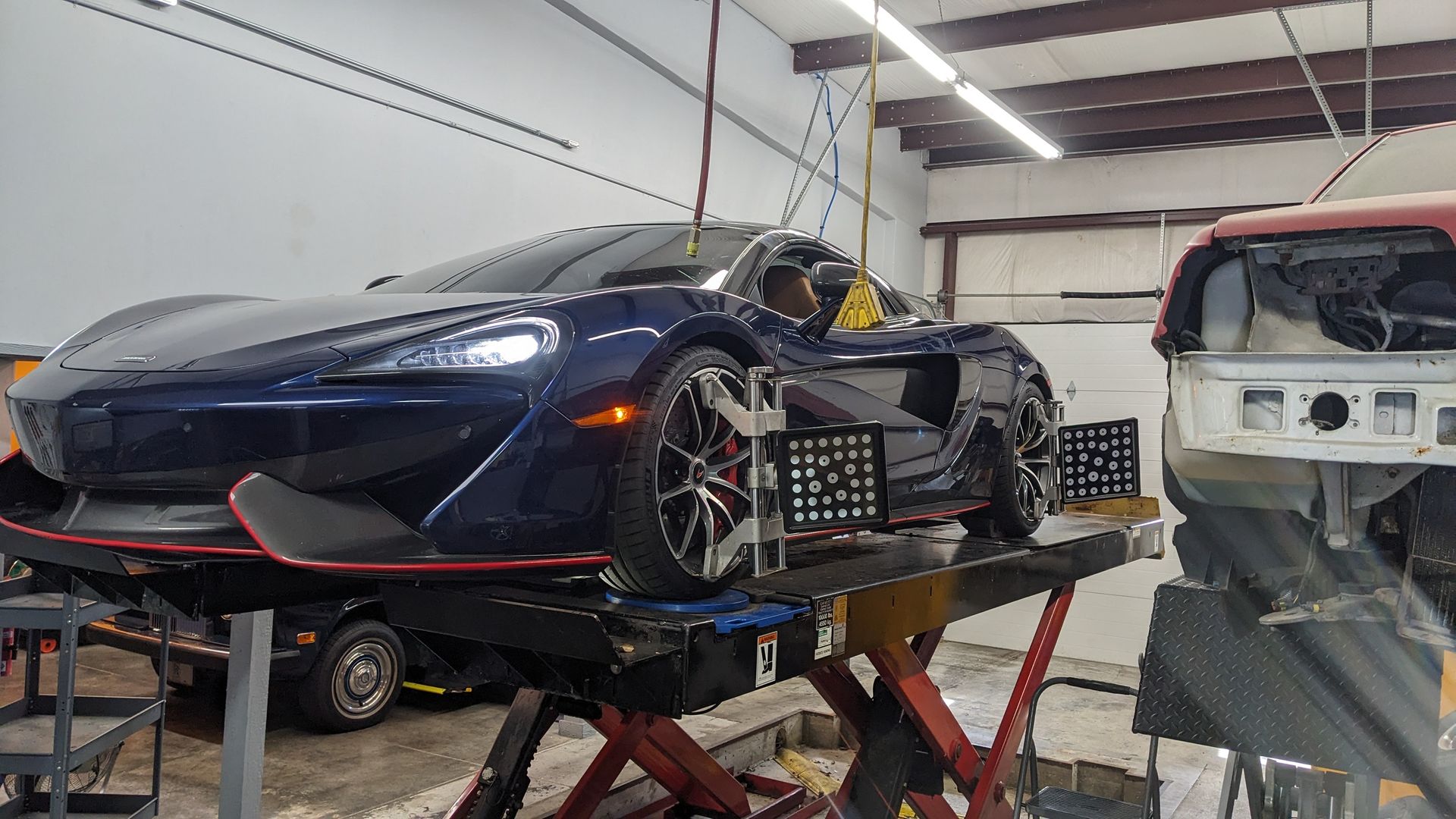 A blue sports car is sitting on a lift in a garage.