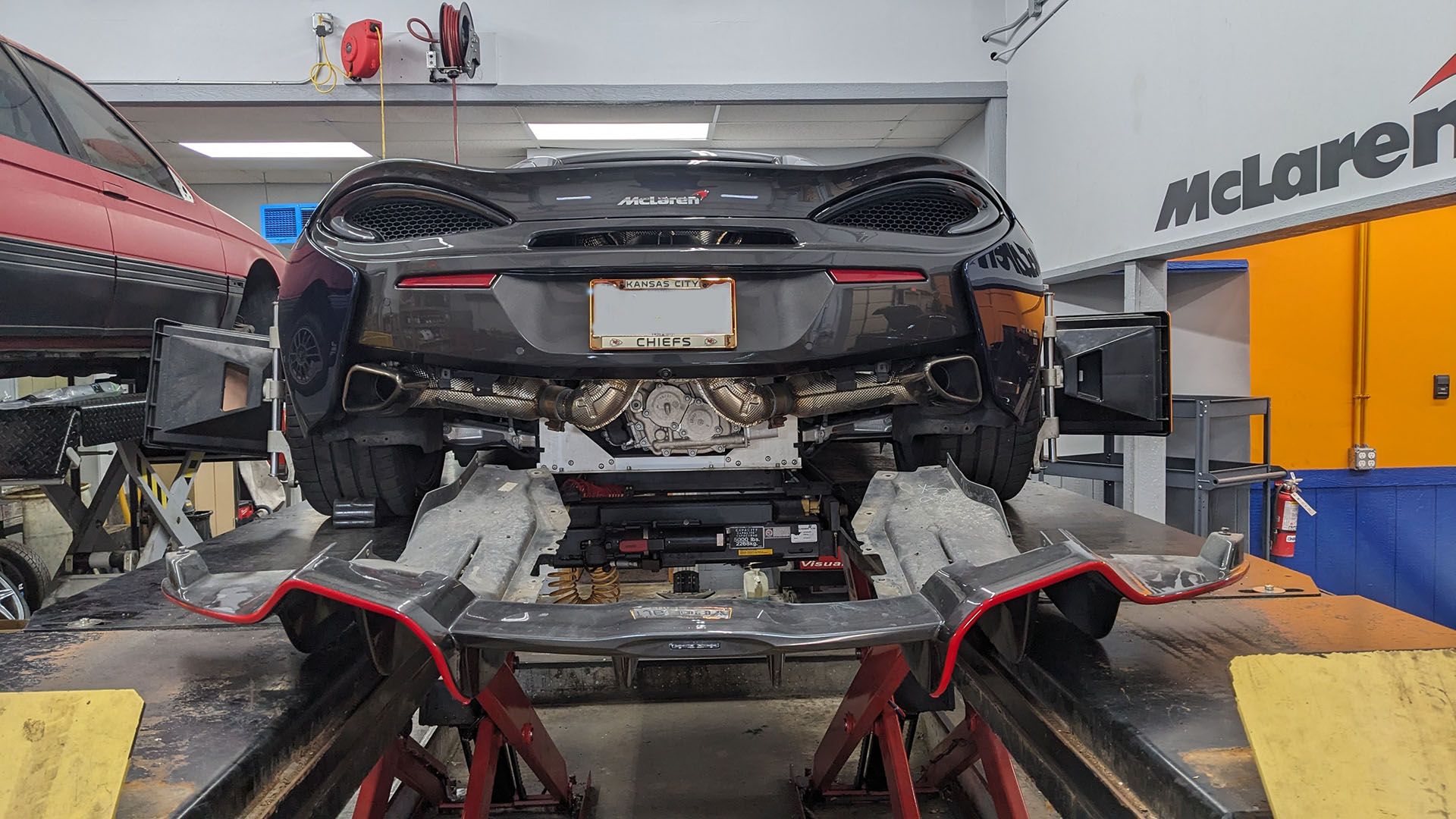 A car is sitting on a lift in a garage.
