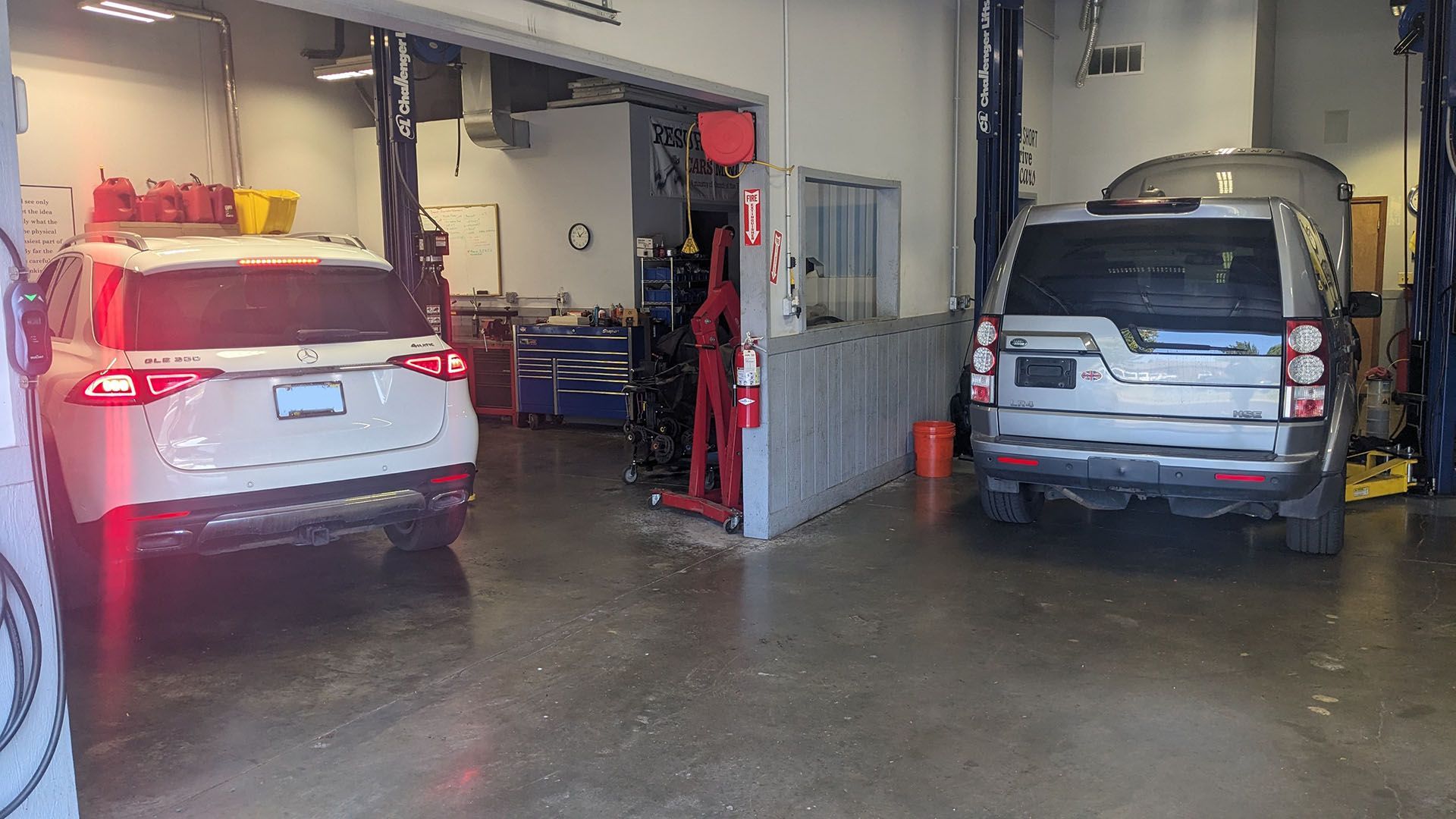 A couple of cars are parked in a garage.