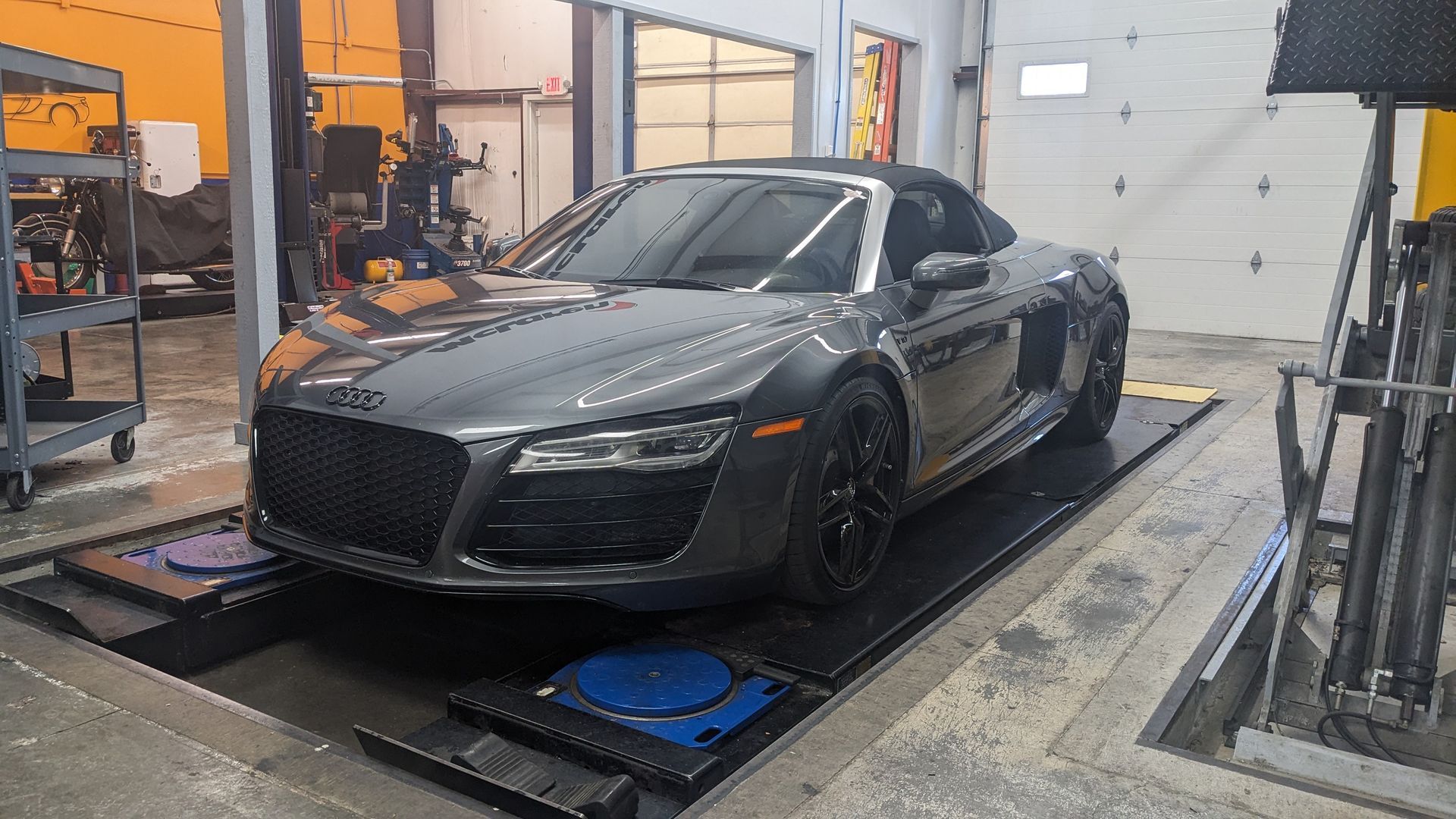 A car is sitting on a lift in a garage.