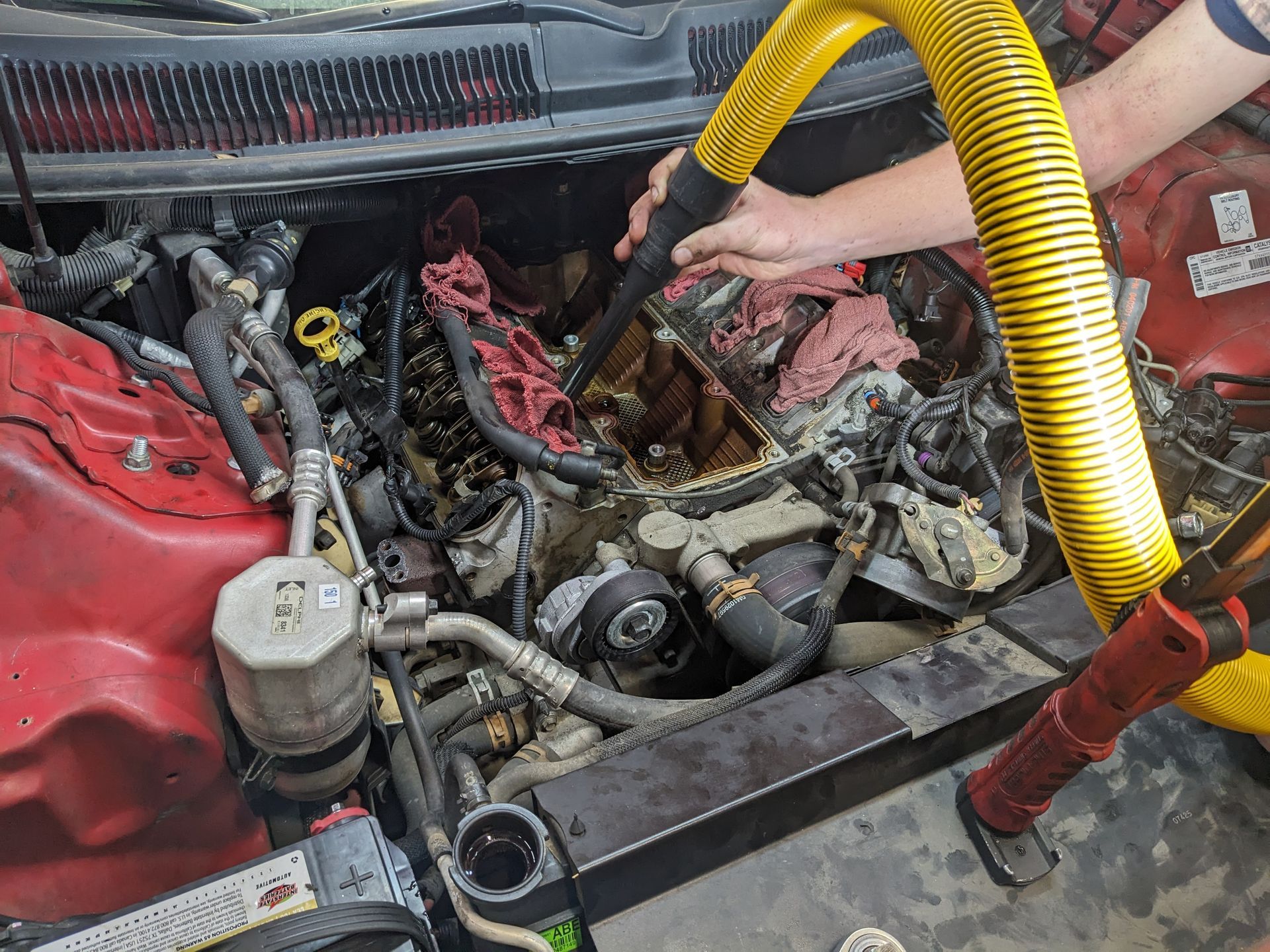 A person is using a vacuum cleaner to clean the engine of a car.