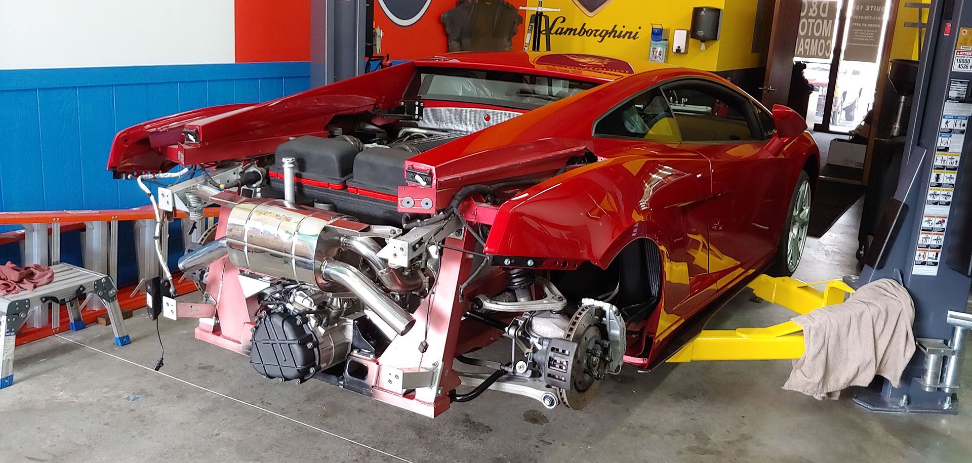 A red sports car is sitting on a lift in a garage.