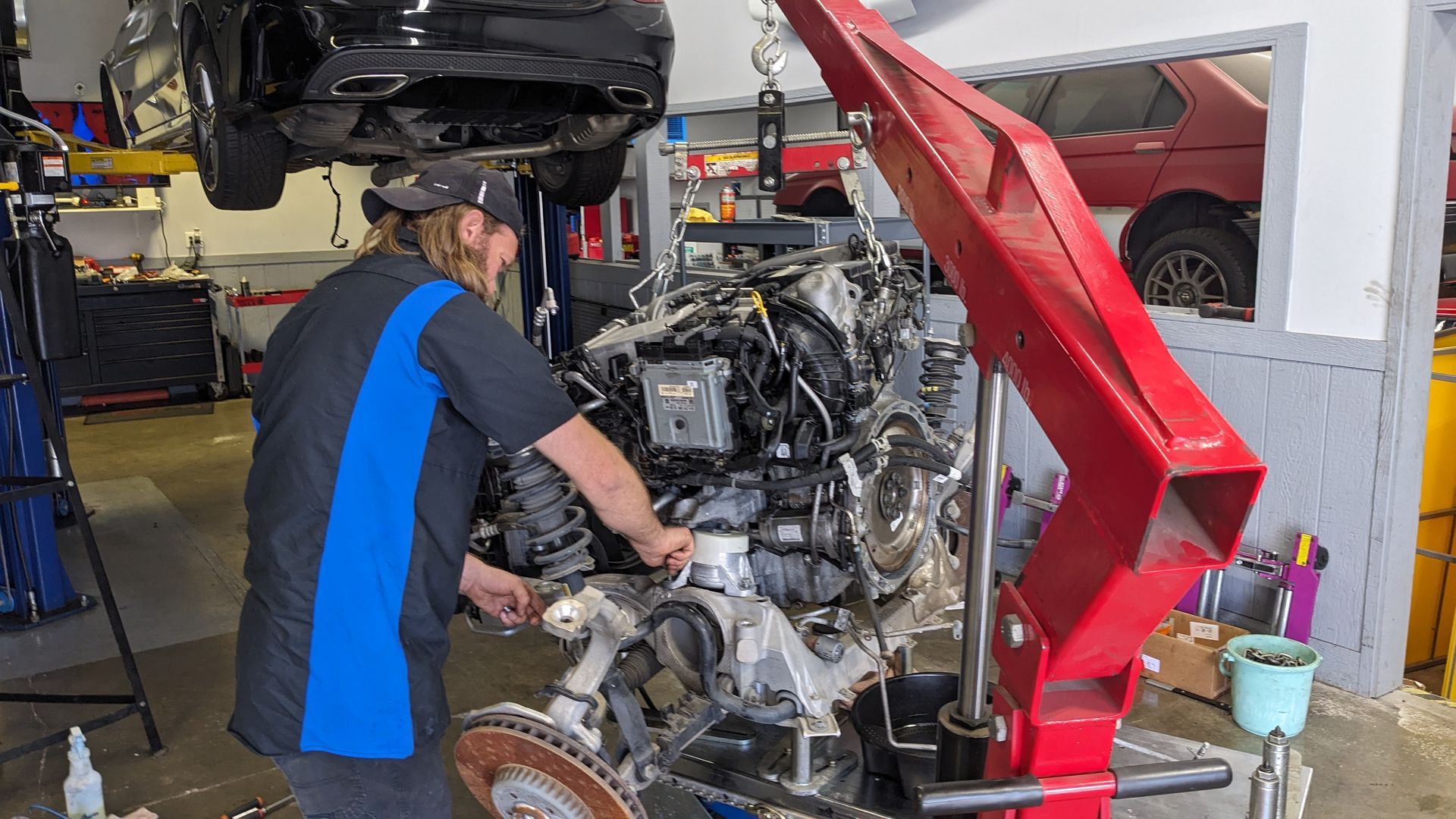 A man is working on a car engine in a garage.