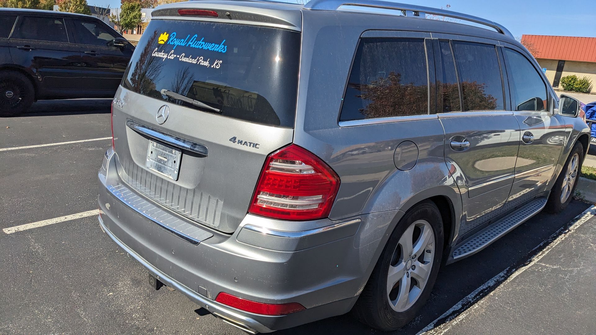 A silver mercedes benz gl 550 is parked in a parking lot.