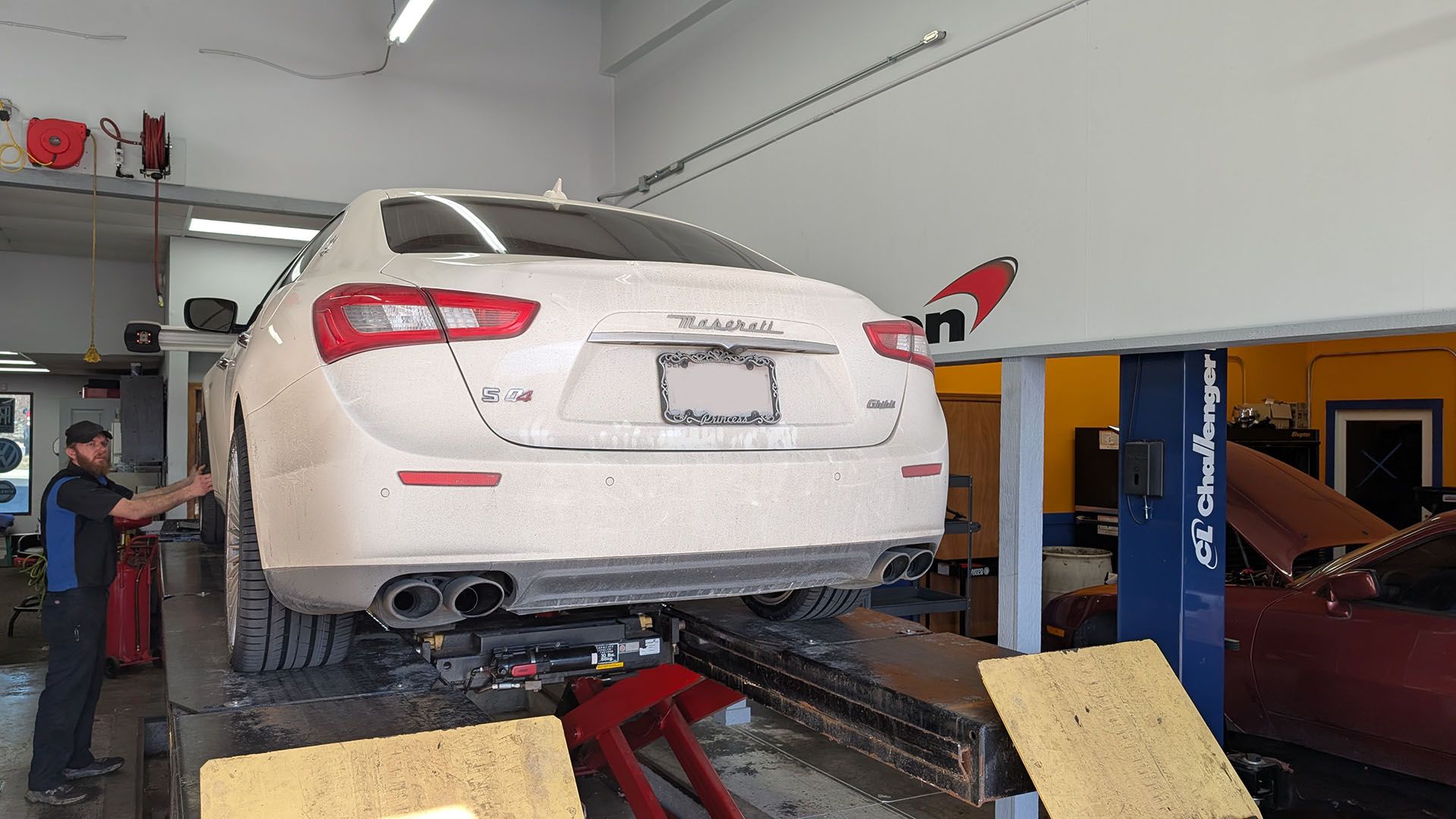 A white car is sitting on a lift in a garage.
