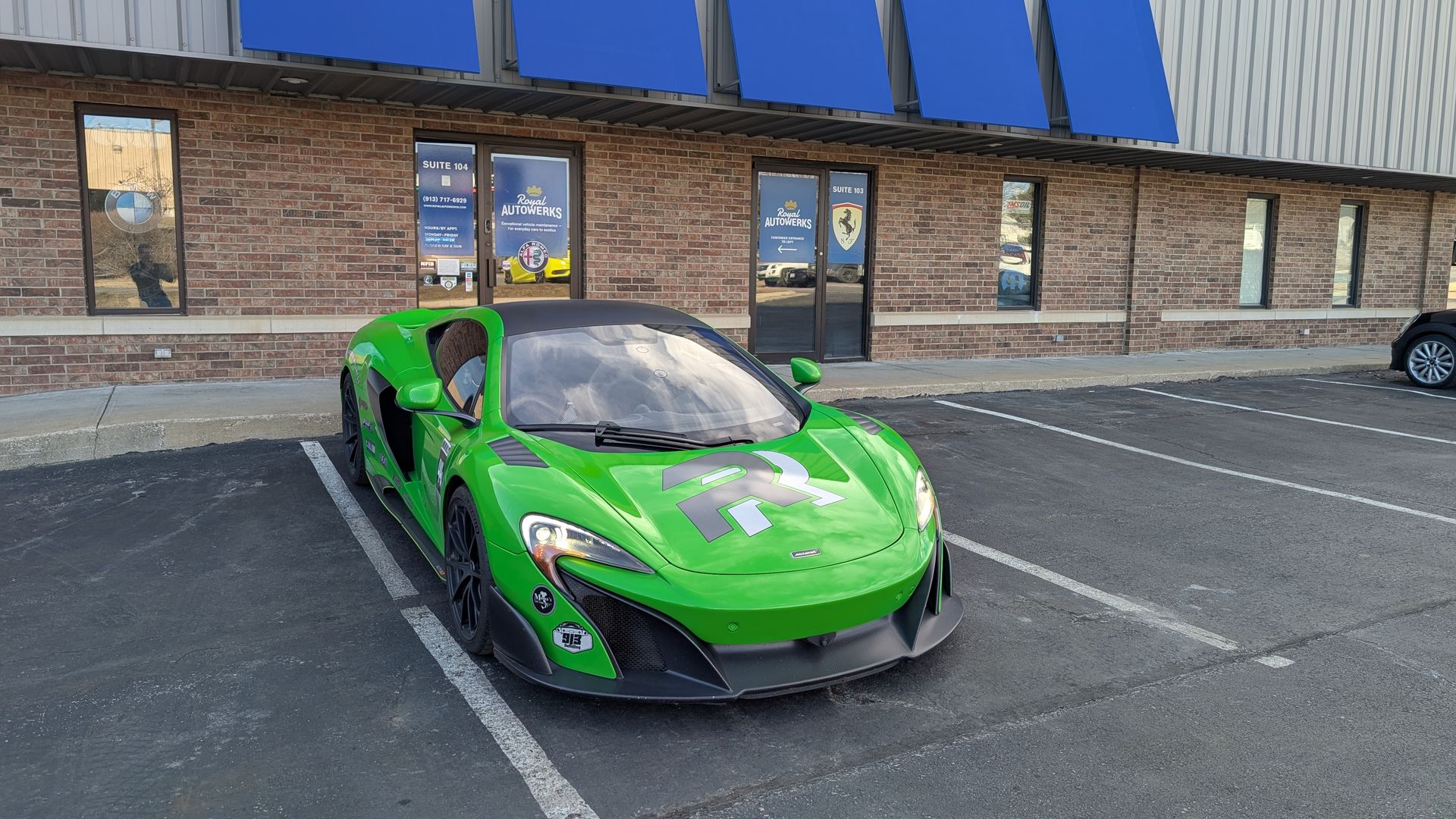 A green sports car is parked in a parking lot in front of a building.