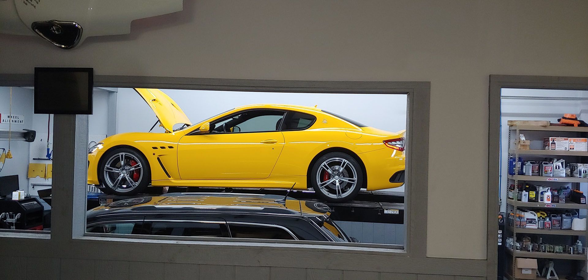 A yellow sports car is sitting on a lift in a garage.