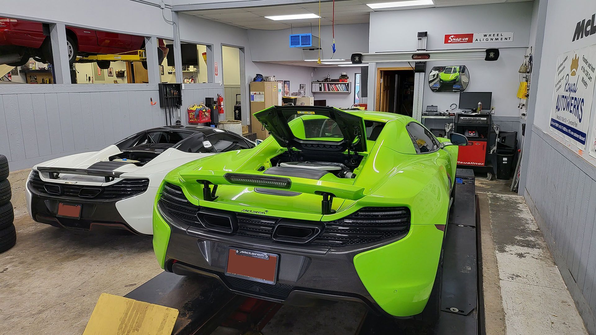 A green and white sports car is parked in a garage.