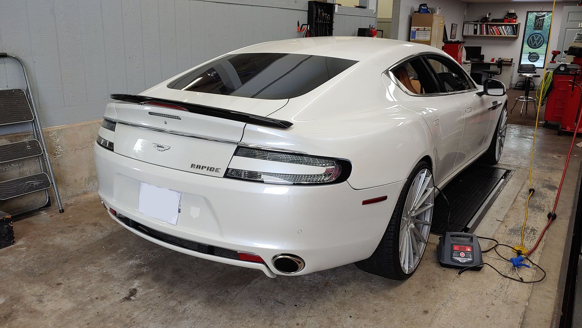 A white car is sitting on a ramp in a garage.