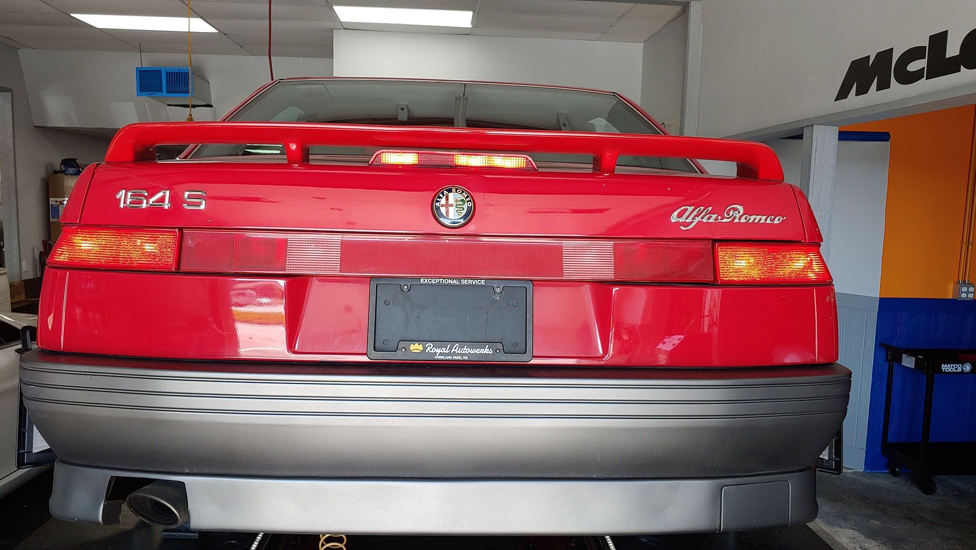 A red alfa romeo is parked in a garage