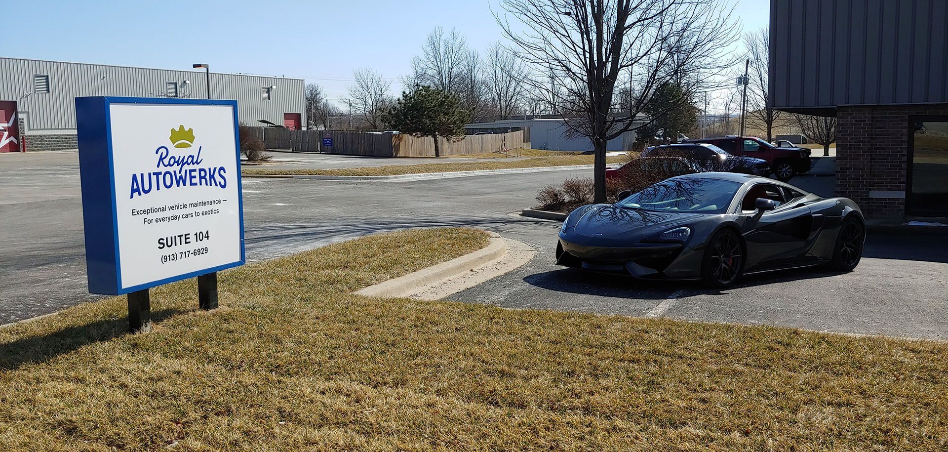 A car is parked in front of a sign that says ' super auto care ' on it.