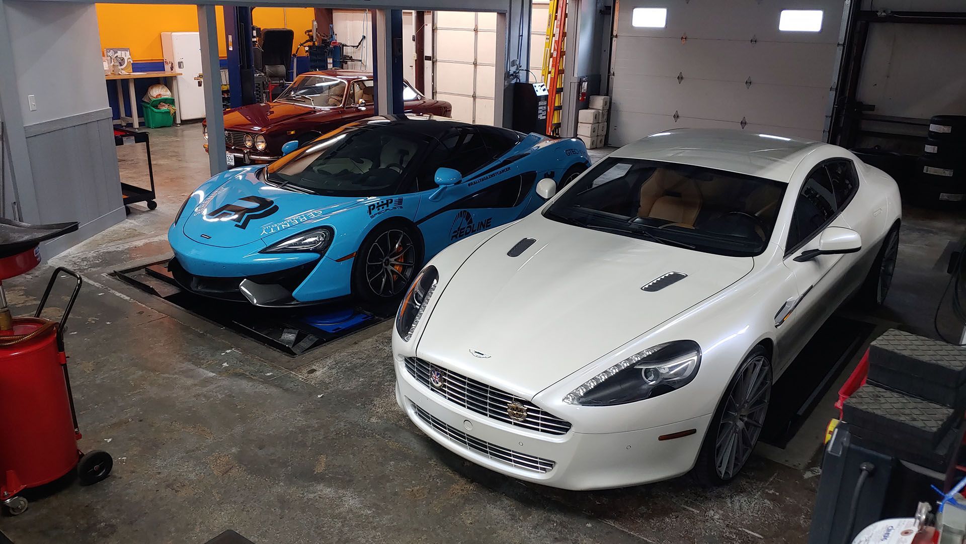 Two sports cars are parked next to each other in a garage.