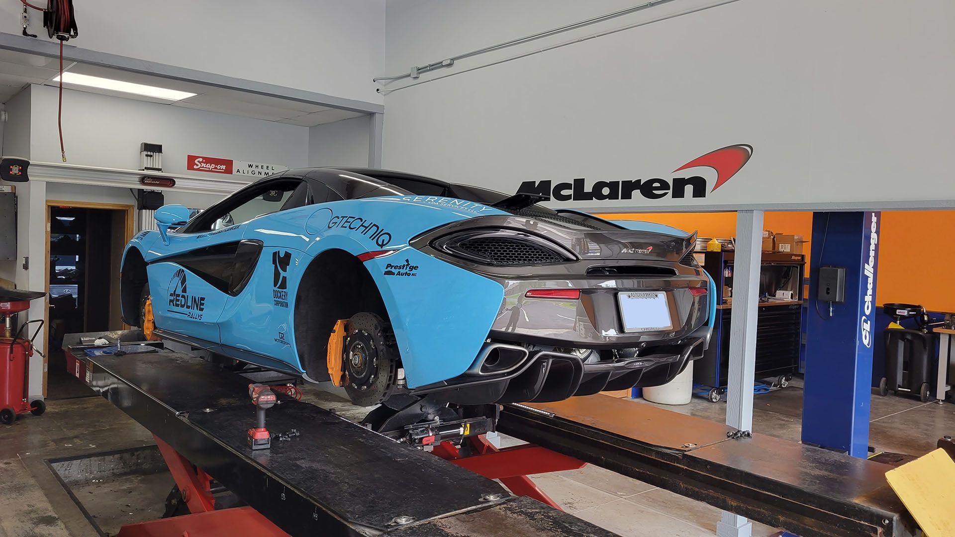 A blue mclaren car is sitting on a lift in a garage.