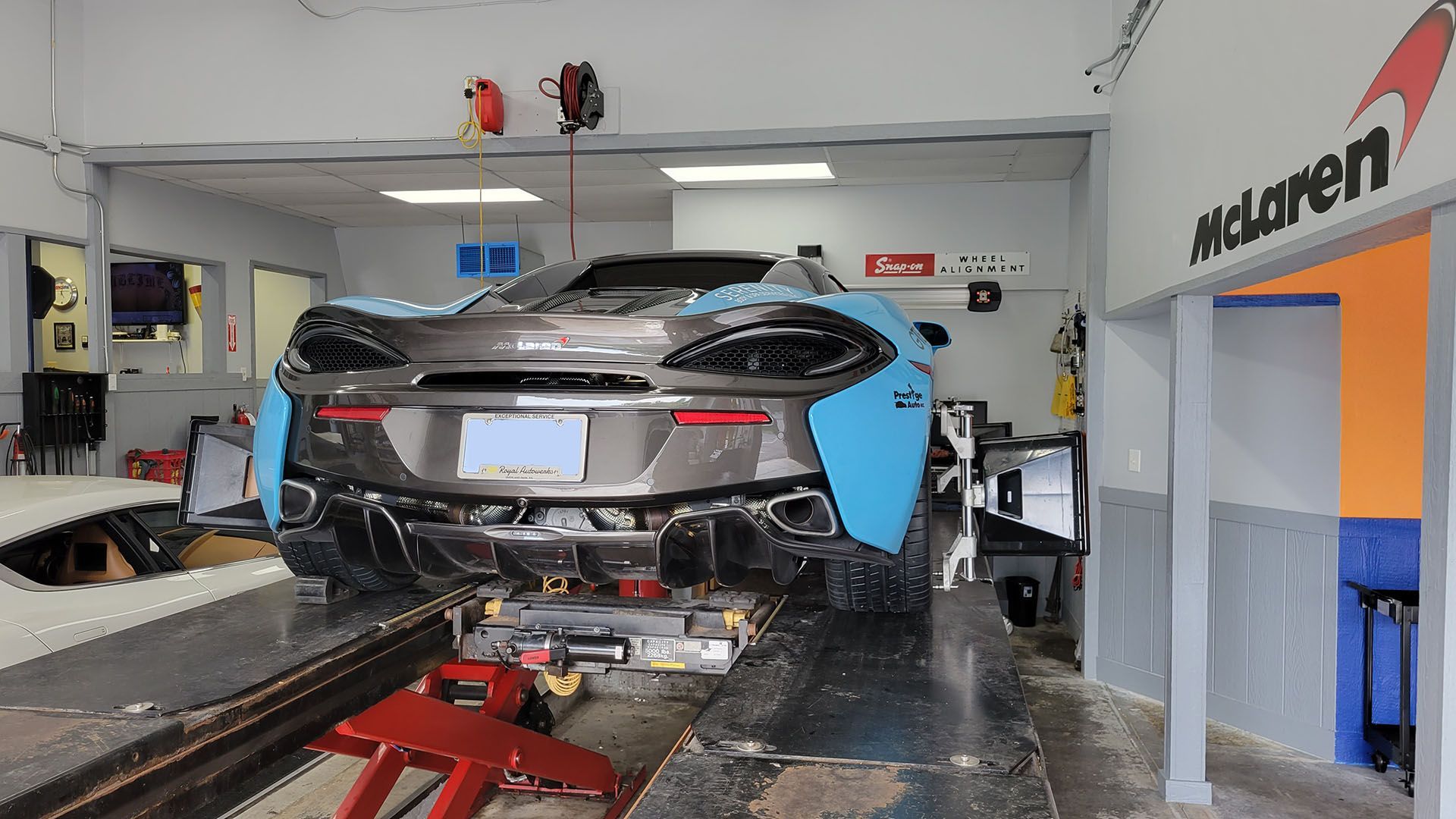 A mclaren car is sitting on a lift in a garage.