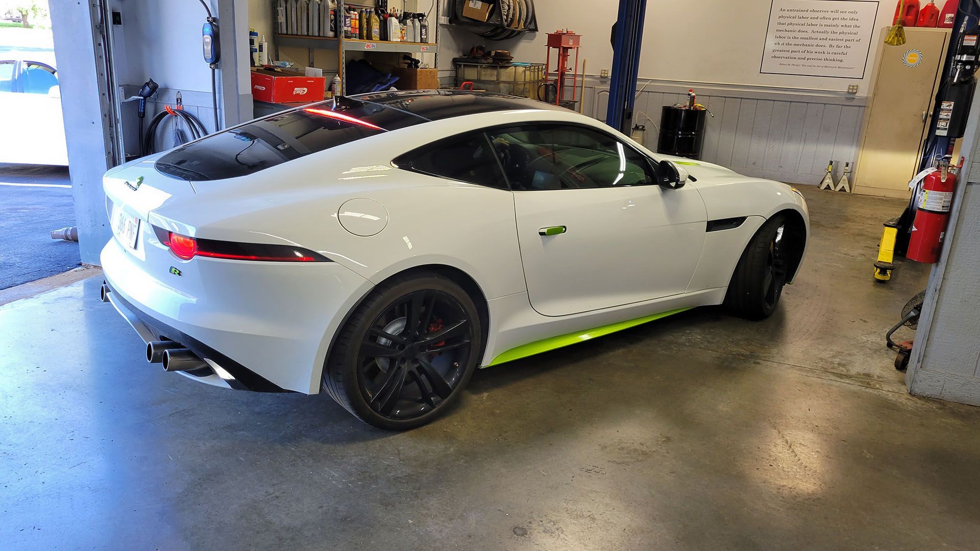 A white sports car is parked in a garage.