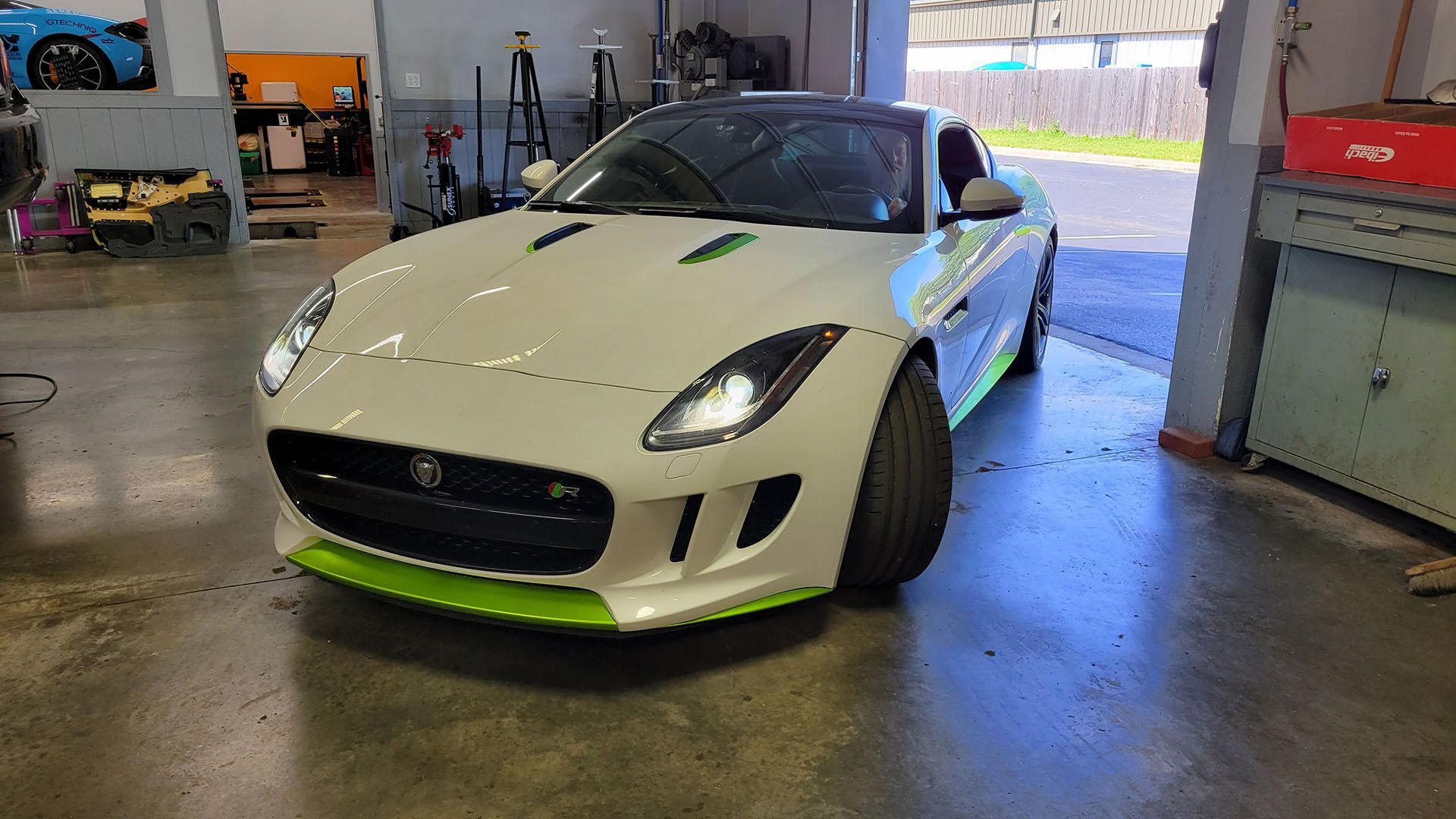 A white and green sports car is parked in a garage.