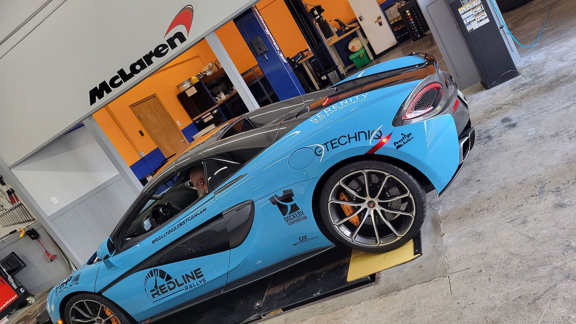 A blue mclaren car is sitting on a lift in a garage.