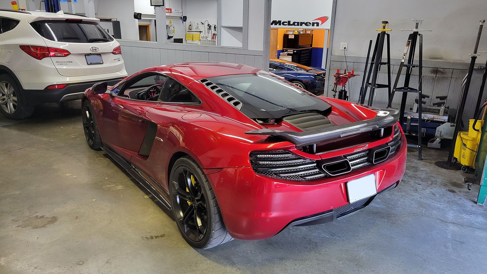 A red sports car is parked in a garage next to a white suv.