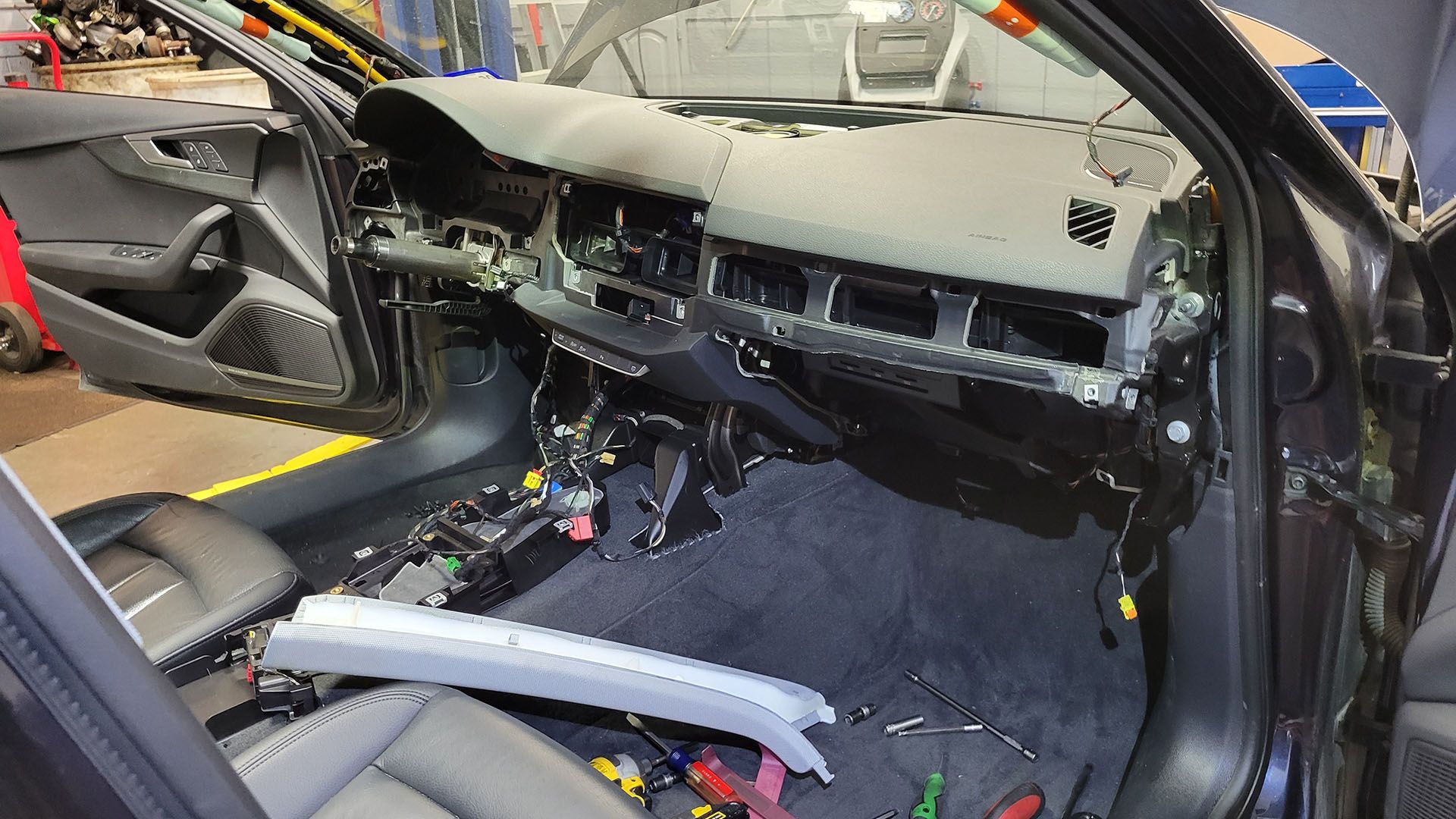 The interior of a car is being dismantled in a garage.