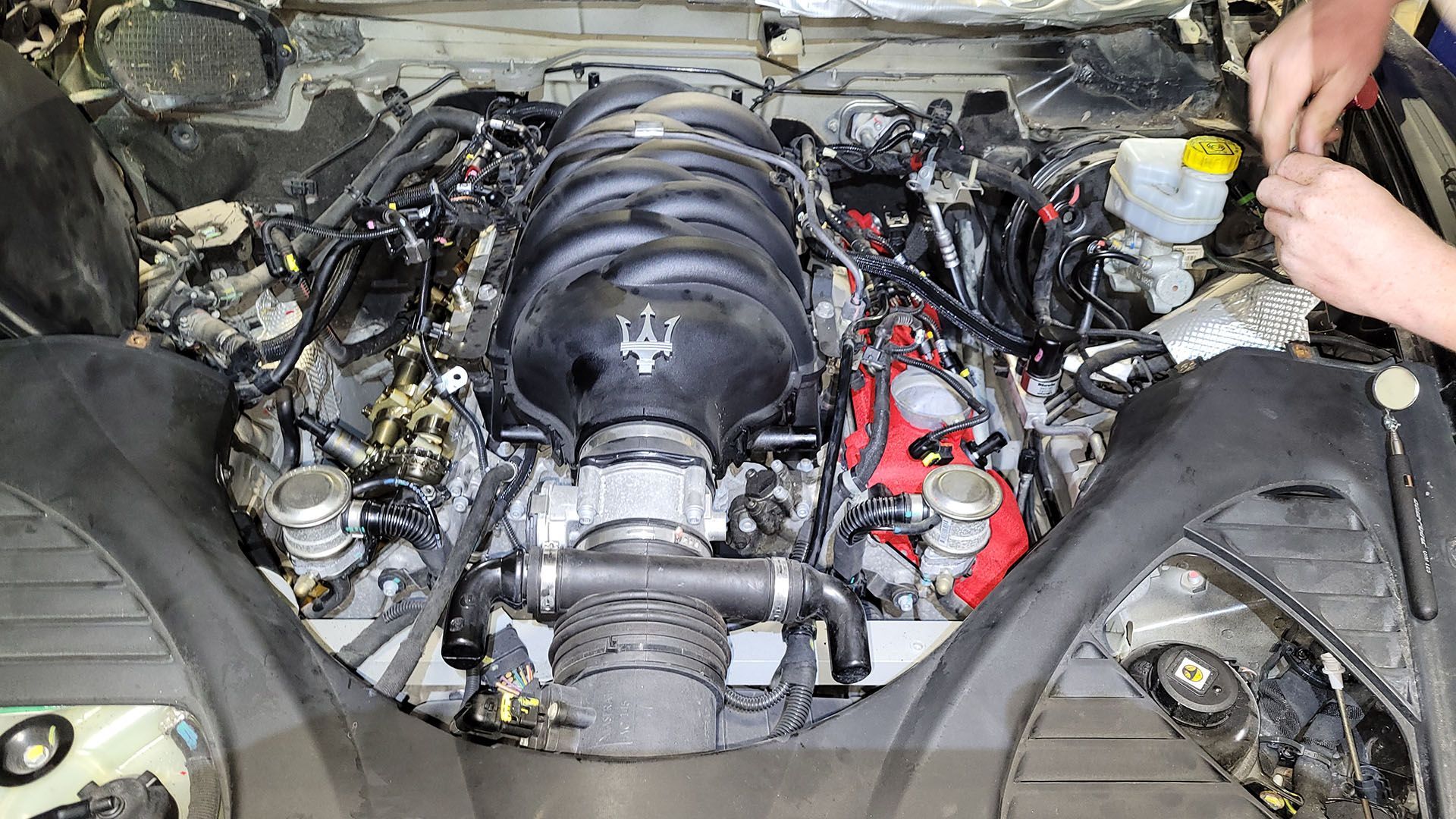 A man is working on the engine of a car.