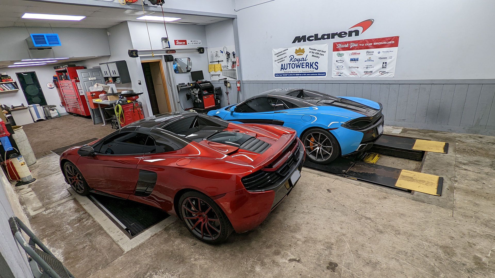 Two sports cars are parked next to each other in a garage.
