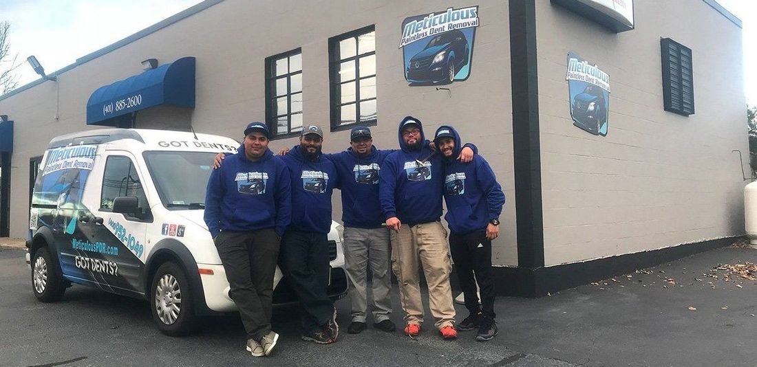 A group of men are posing for a picture in front of a van.