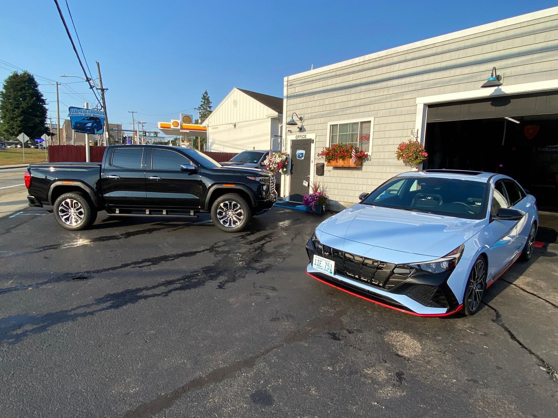 A black truck and a light blue car are parked in front of a garage
