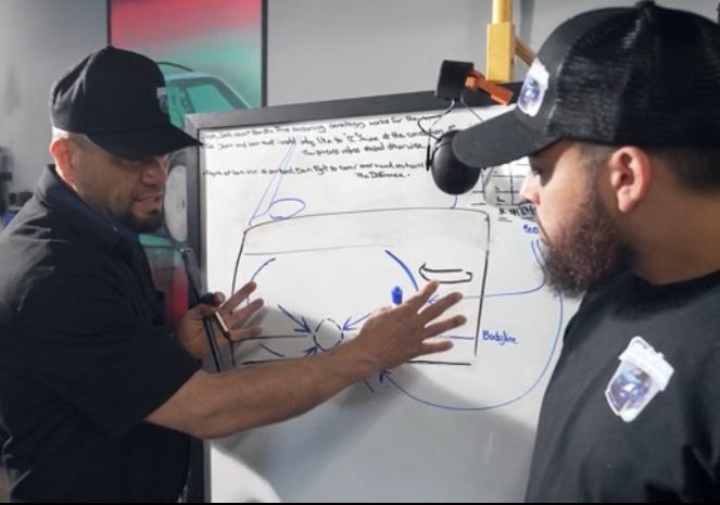 Two men are looking at a drawing on a whiteboard