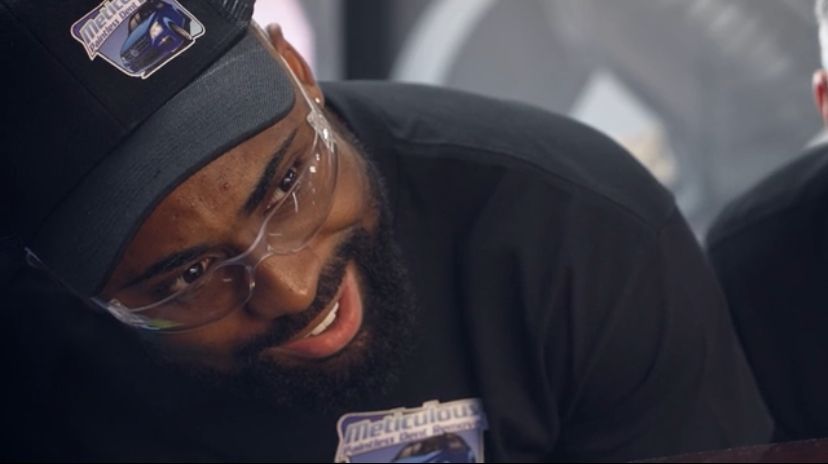 A man wearing a hat and glasses is smiling