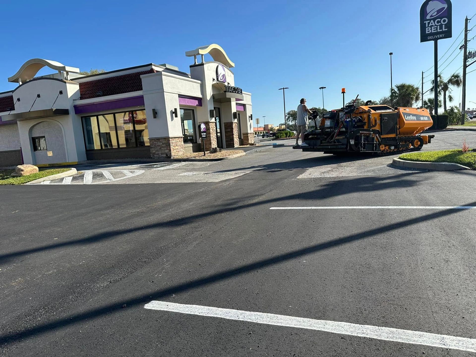 Damaged roadside building with debris and a utility truck parked in a sunny lot