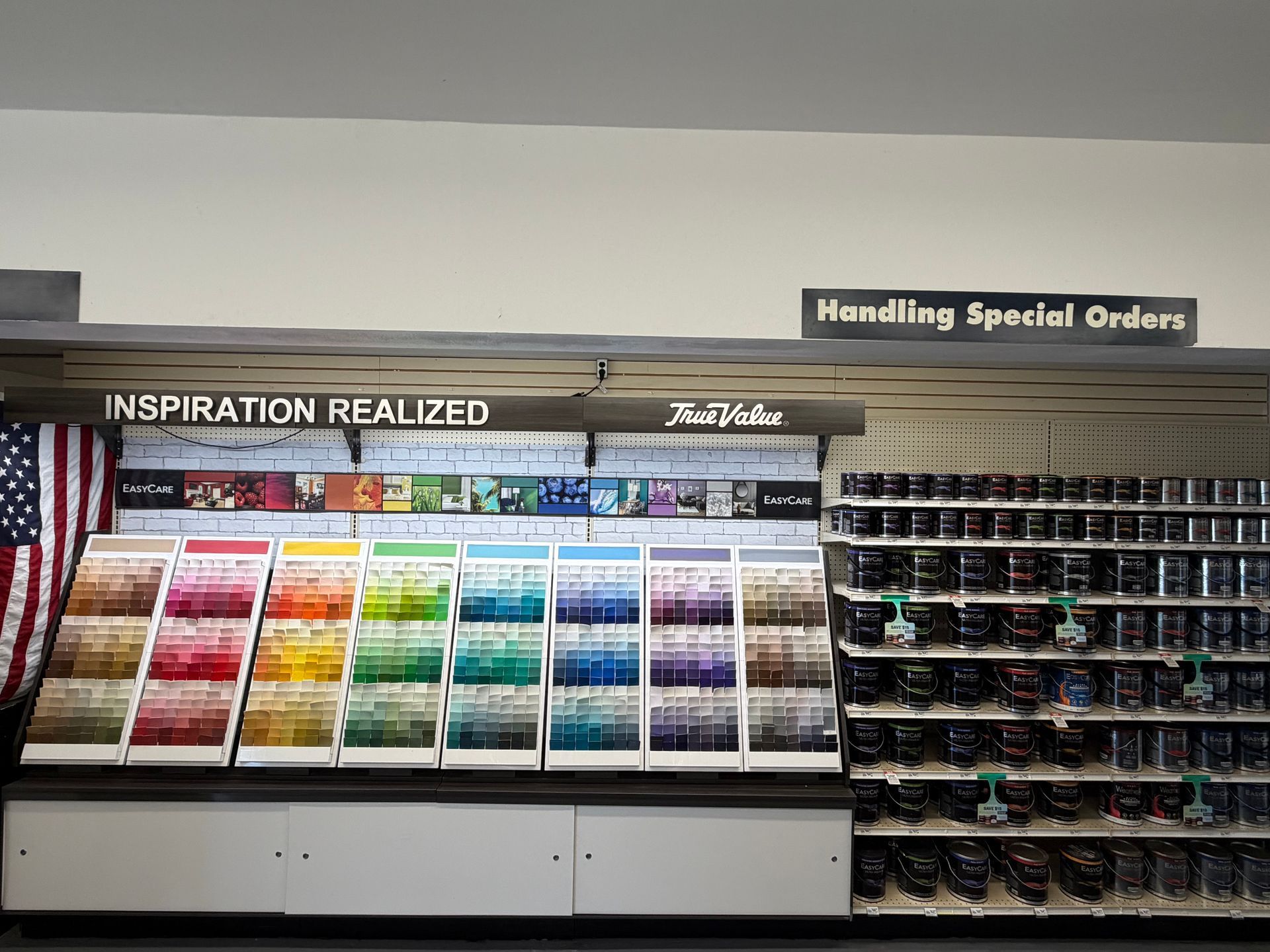 A paint department display wall featuring color swatches, paint cans, and signage for special orders.