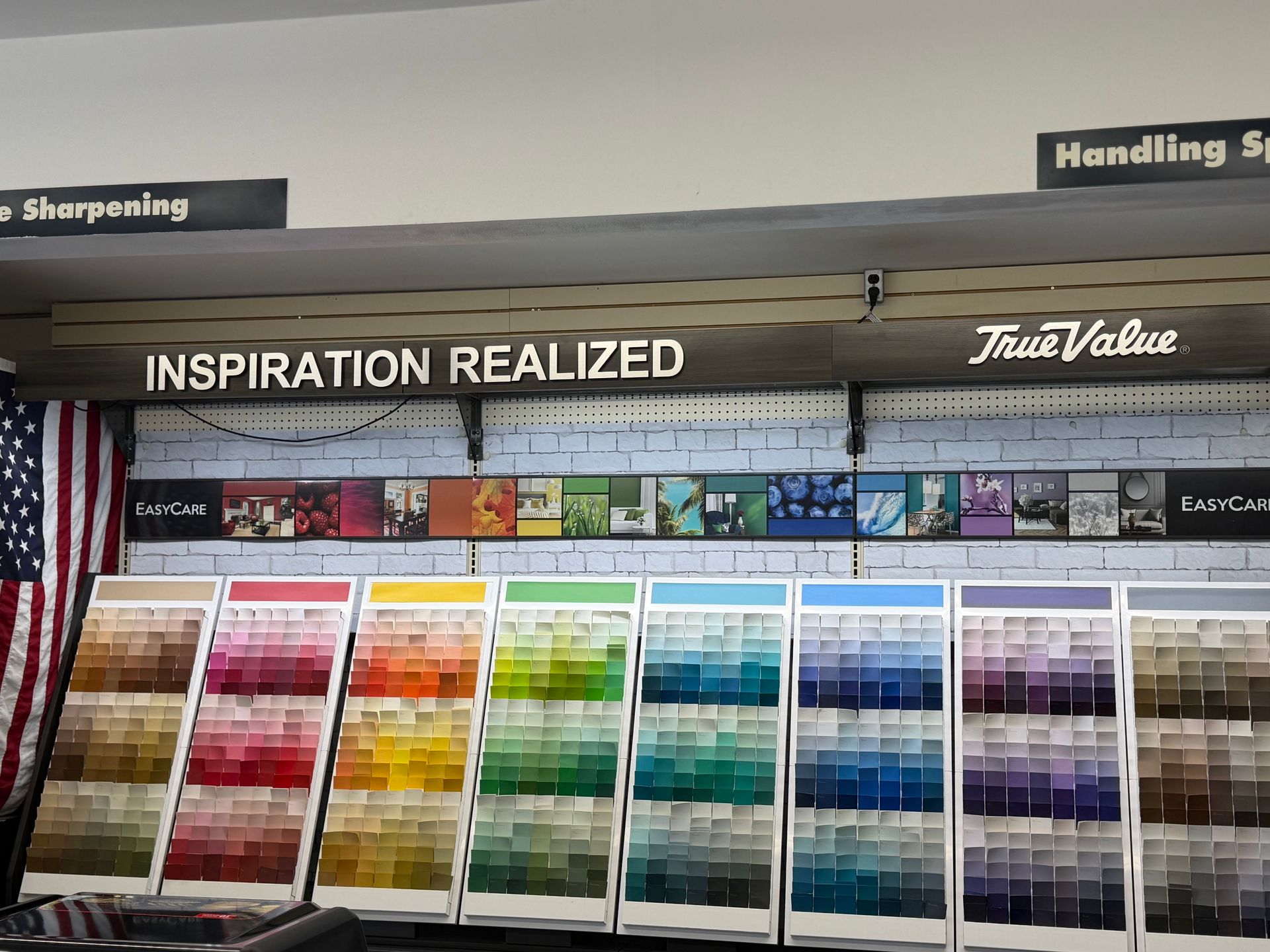 A True Value hardware store paint display with rows of color-coded paint sample cards under a sign reading