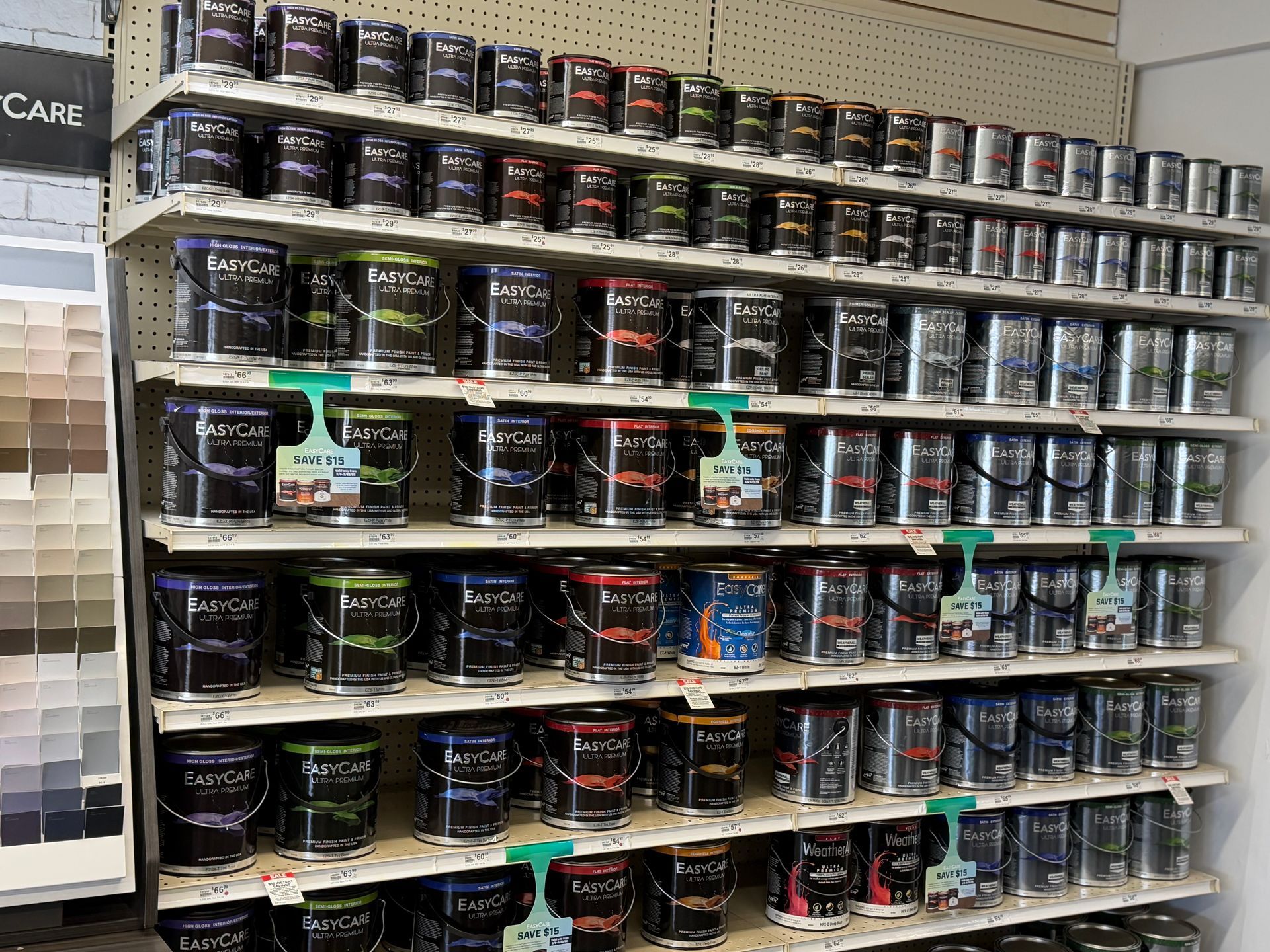 Shelves in a hardware store stocked with rows of labeled paint cans in various colors.