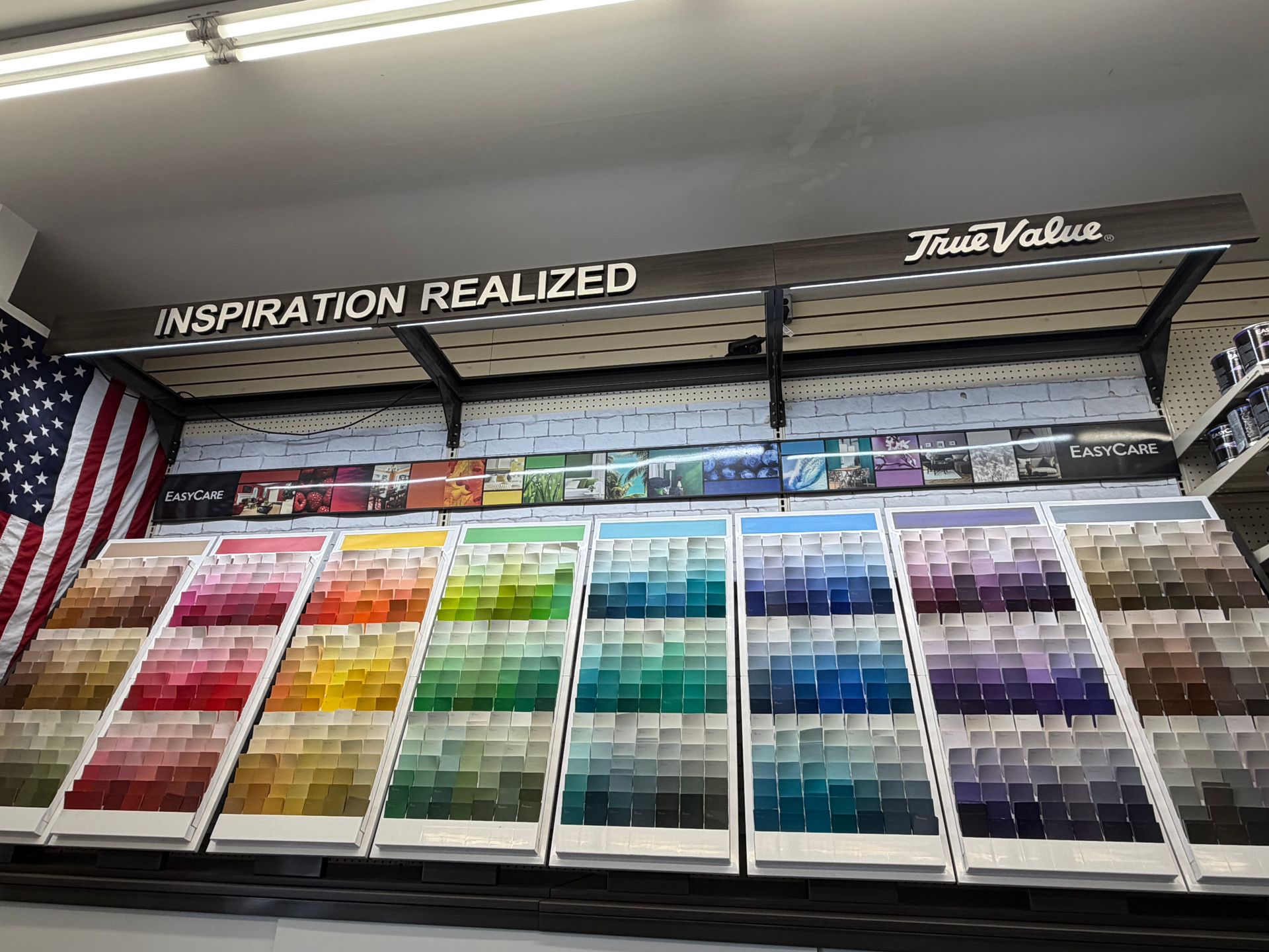 A True Value paint color swatch display featuring a wide spectrum of color samples arranged on a store shelf.